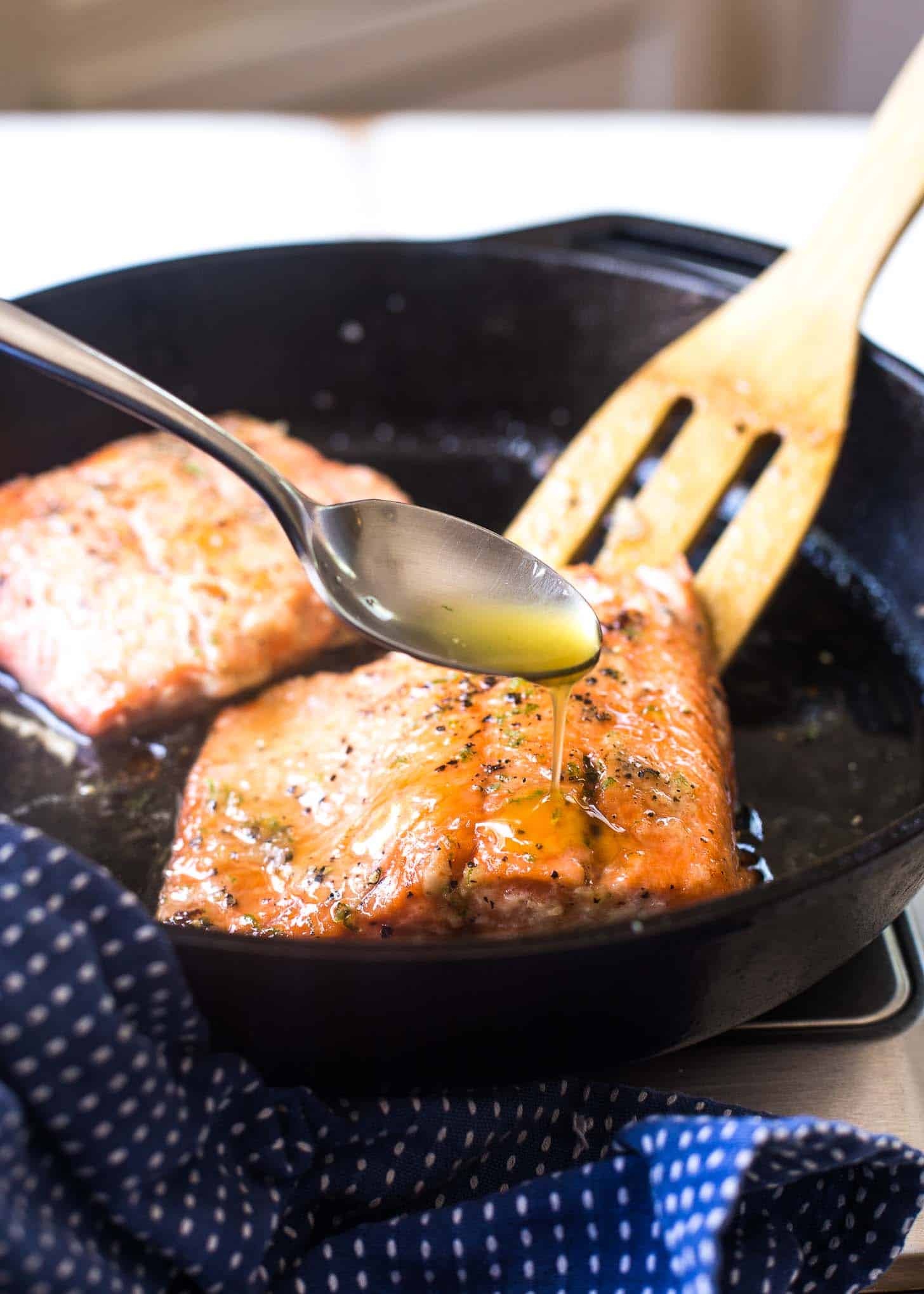 spooning marinade over Salmon in a cast iron skillet