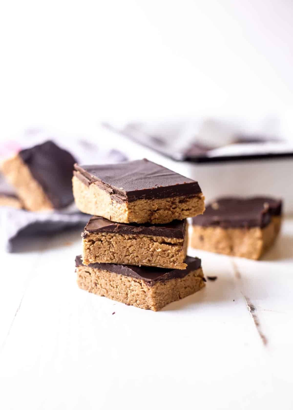 No Bake Chocolate Peanut Butter Bars stacked on a white table