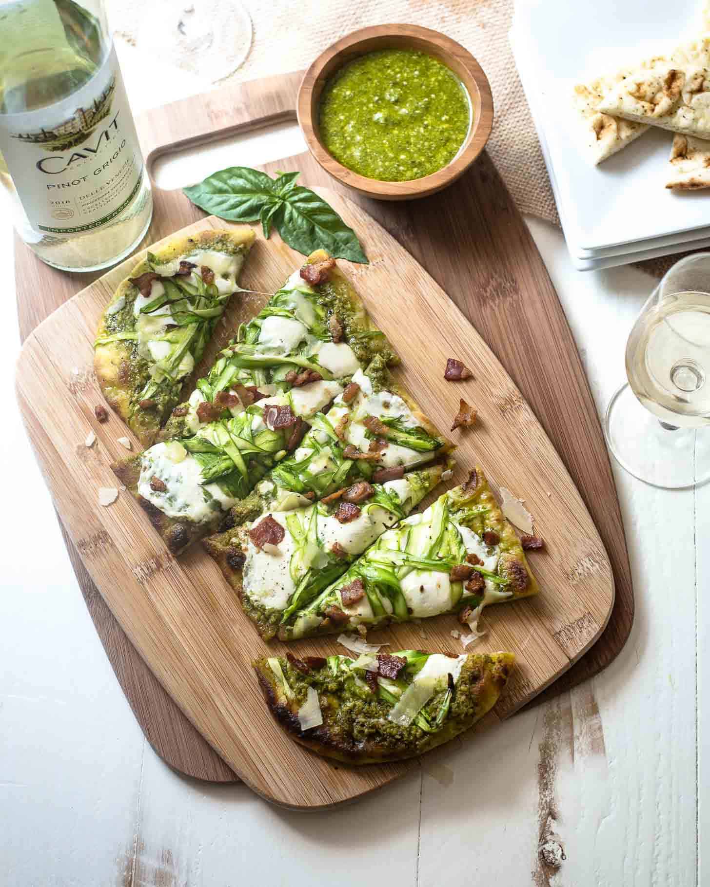 Pesto Flatbread with Shaved Asparagus and Bacon sliced on a wooden cutting board