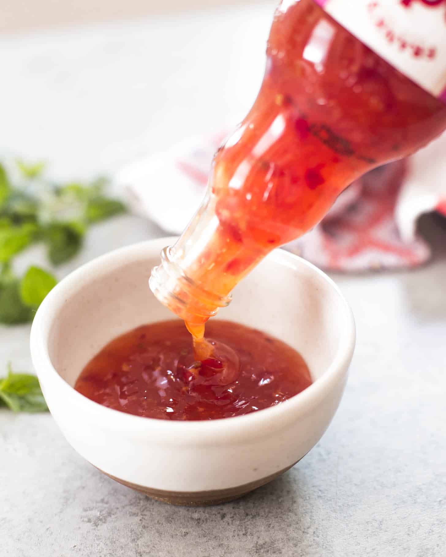 pouring Thai Sweet Chili Sauce into a small white bowl