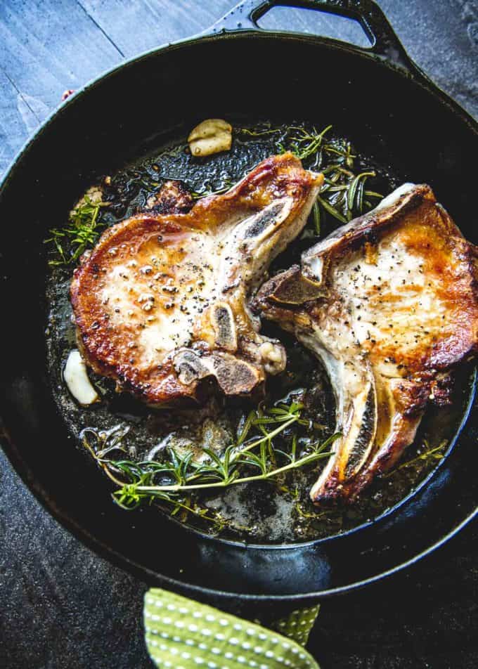 cooking Herb Marinated Pork Chops in a cast iron skillet