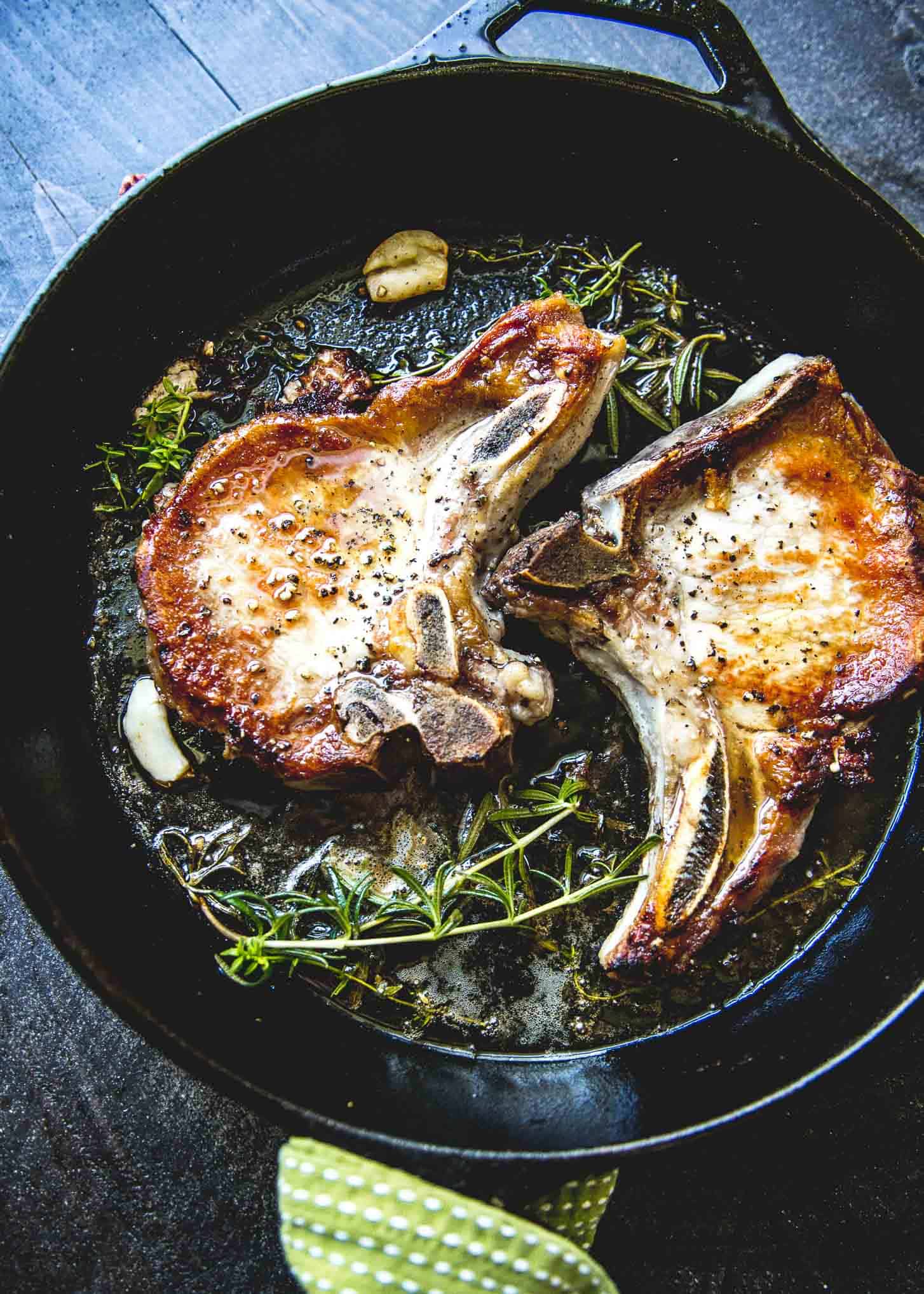 cooking herb marinated pork chops in a cast iron skillet