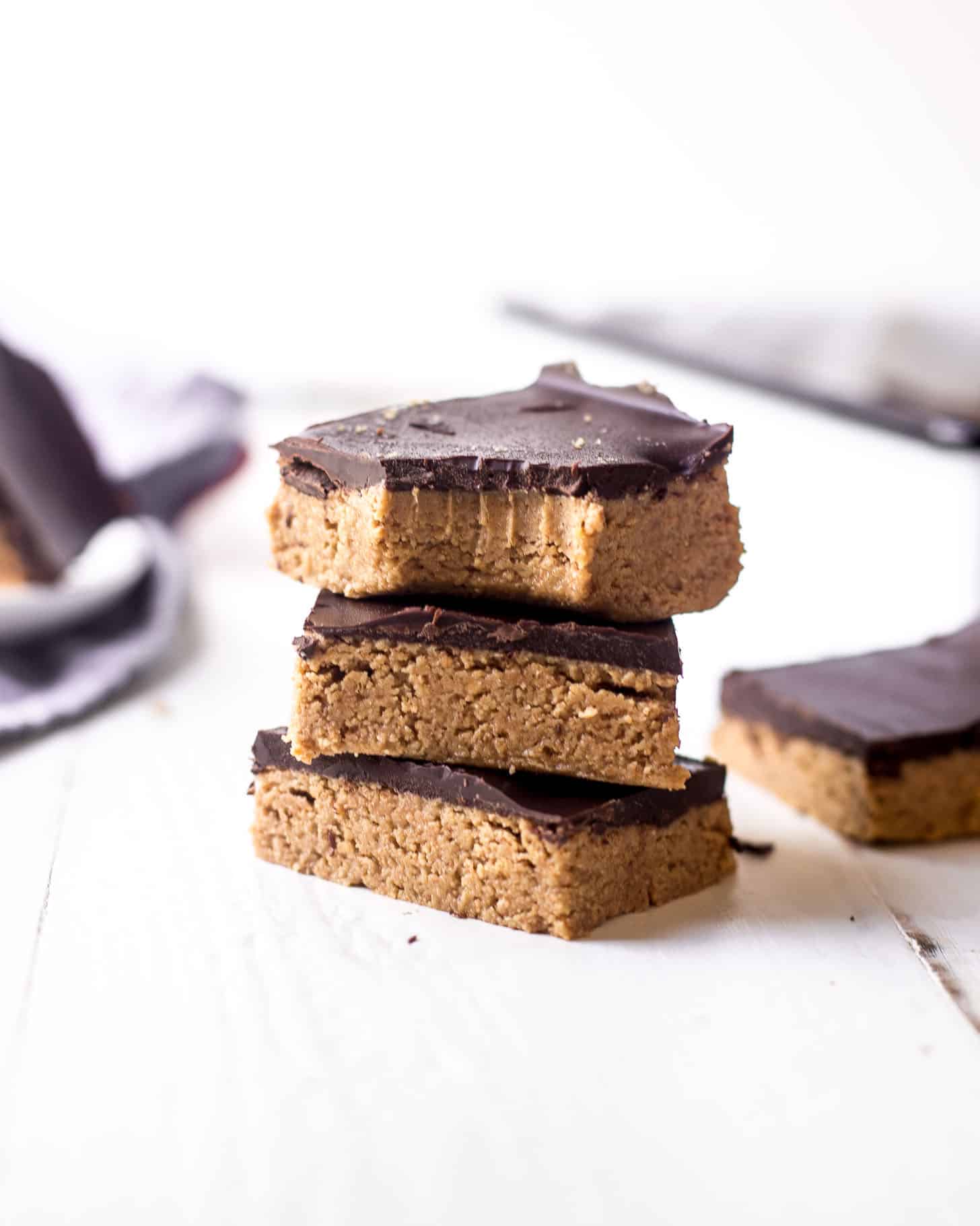 No Bake Chocolate Peanut Butter Bars stacked on a white table