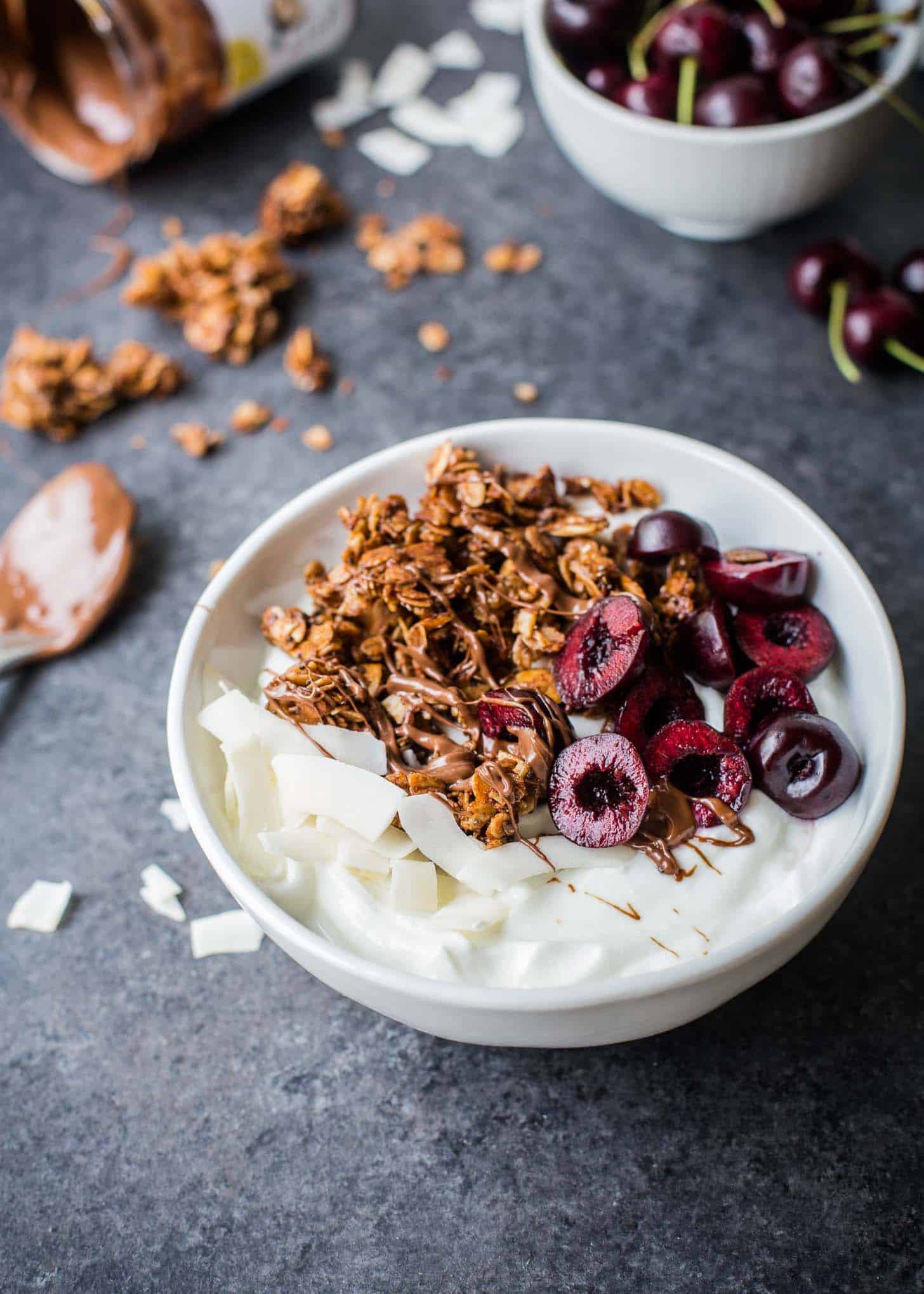 Nutella Granola in a white bowl with coconut and cherries