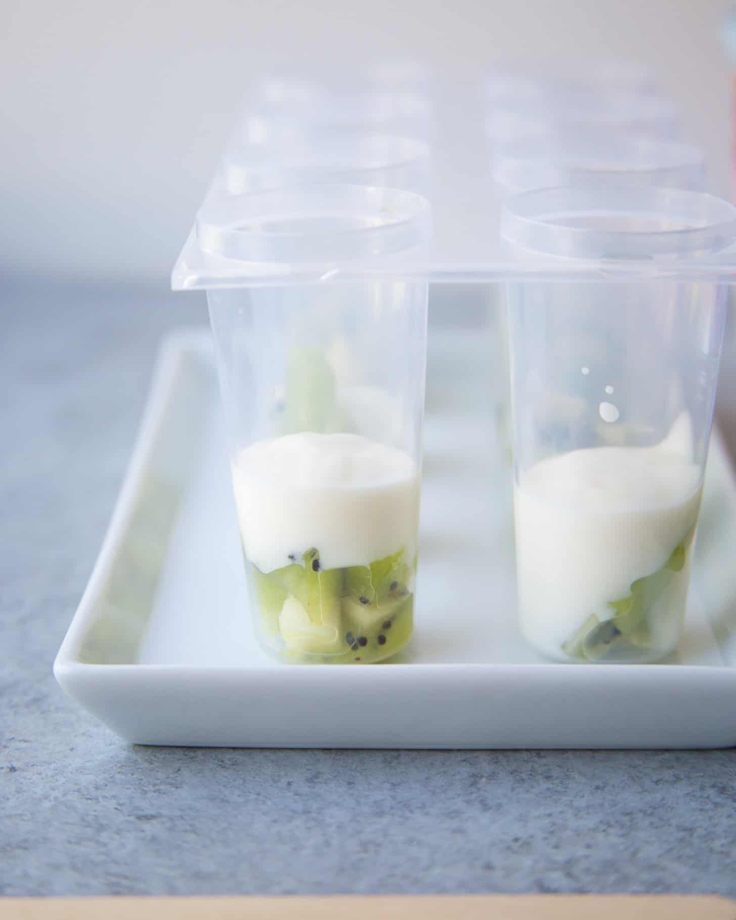 adding fruit and yogurt to popsicle molds