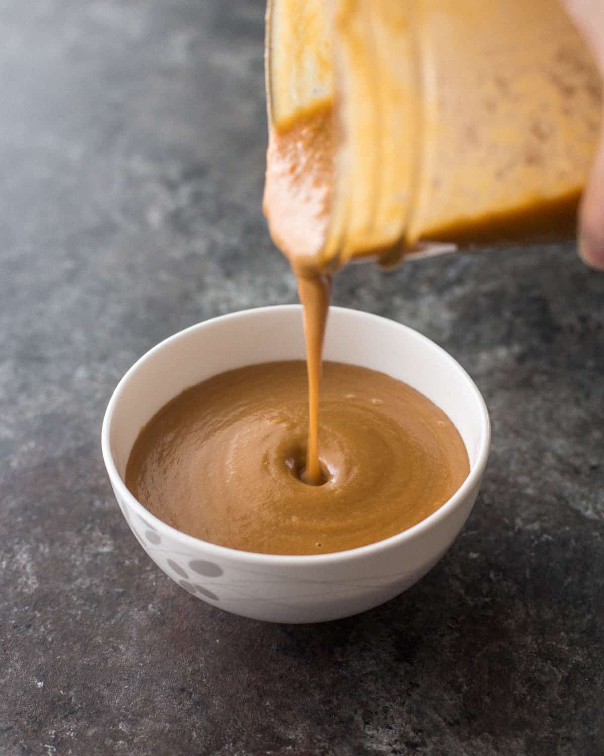 pouring peanut sauce into a bowl