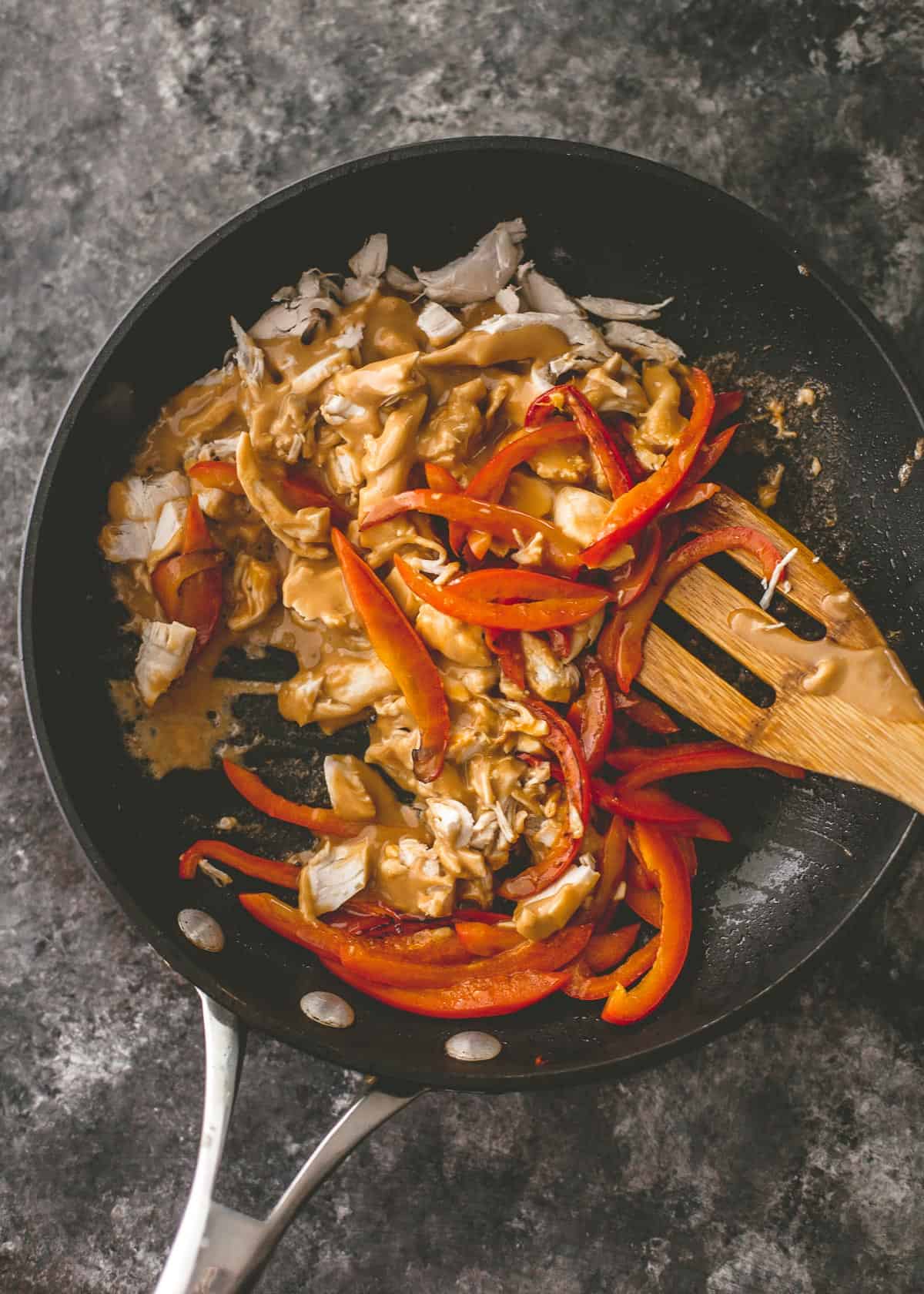 overhead image of stirring peppers and chicken in a cast iron skillet