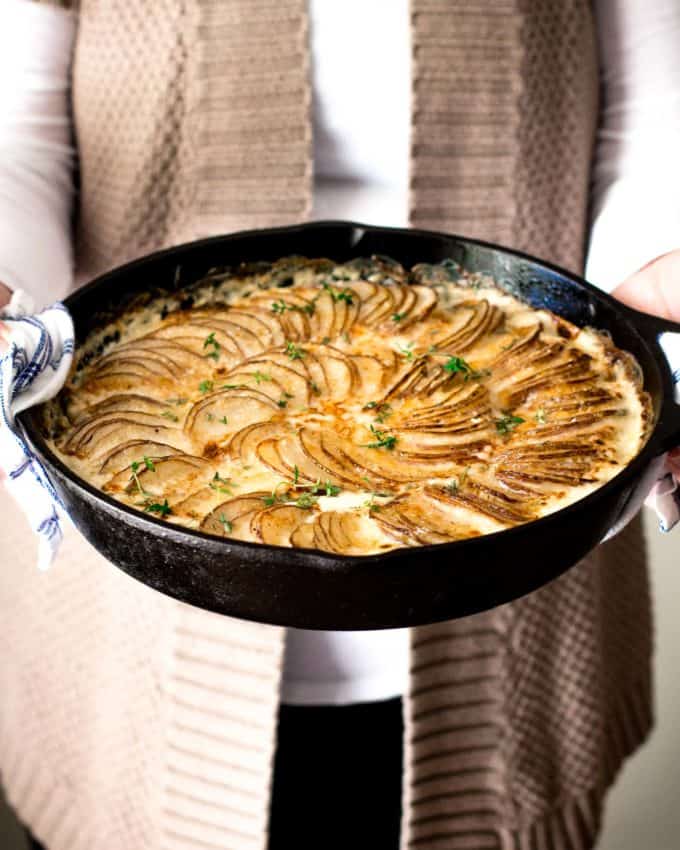 Creamy Au Gratin Potatoes with Kale and Gruyere in a cast iron skillet