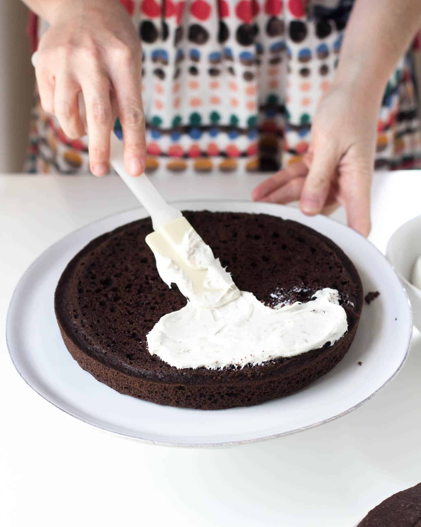 spreading frosting on a chocolate cake
