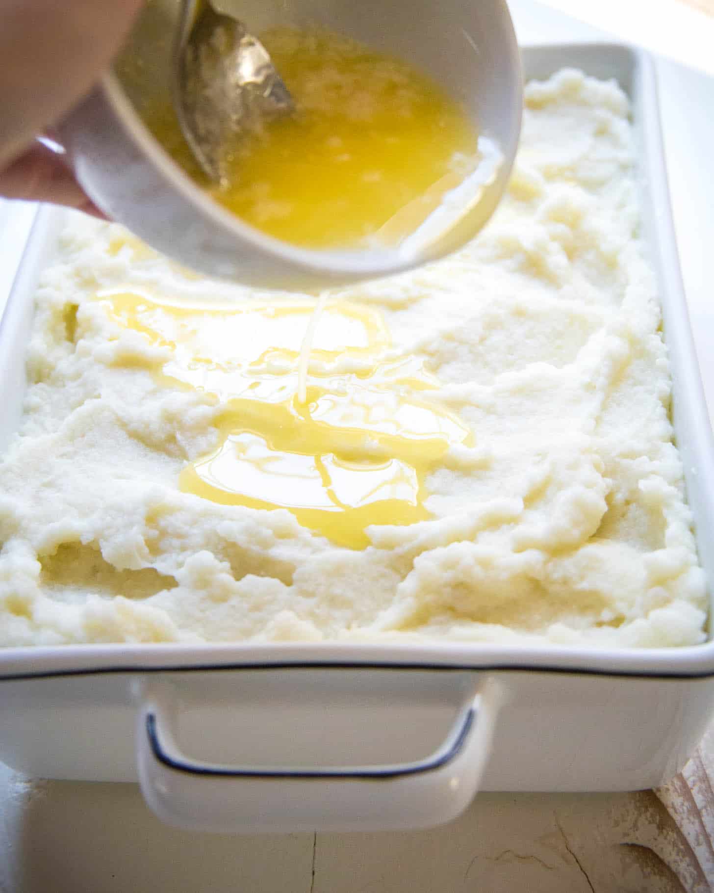 pouring melted butter on mashed potatoes