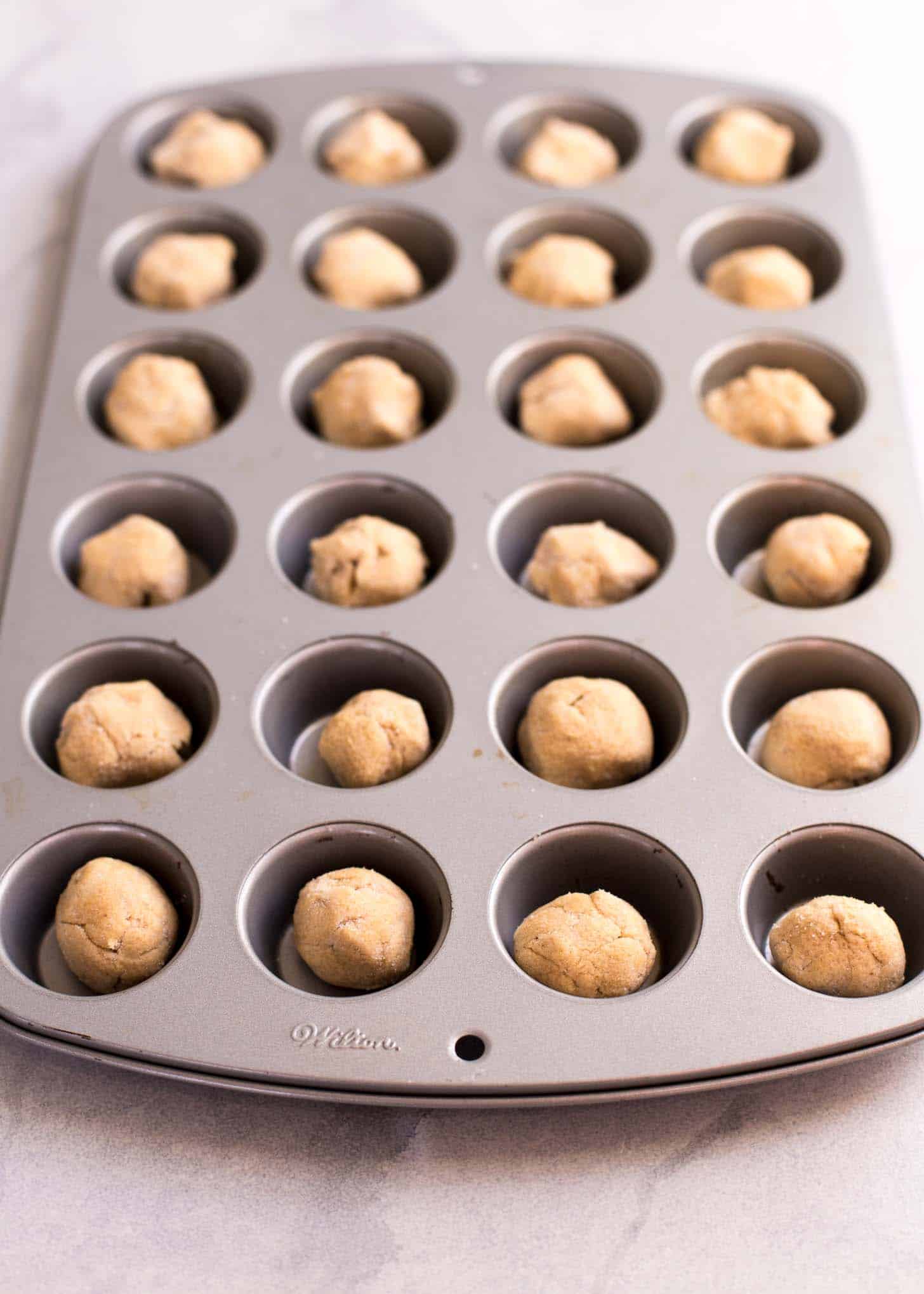 rolled balls of dough in a mini muffin tin