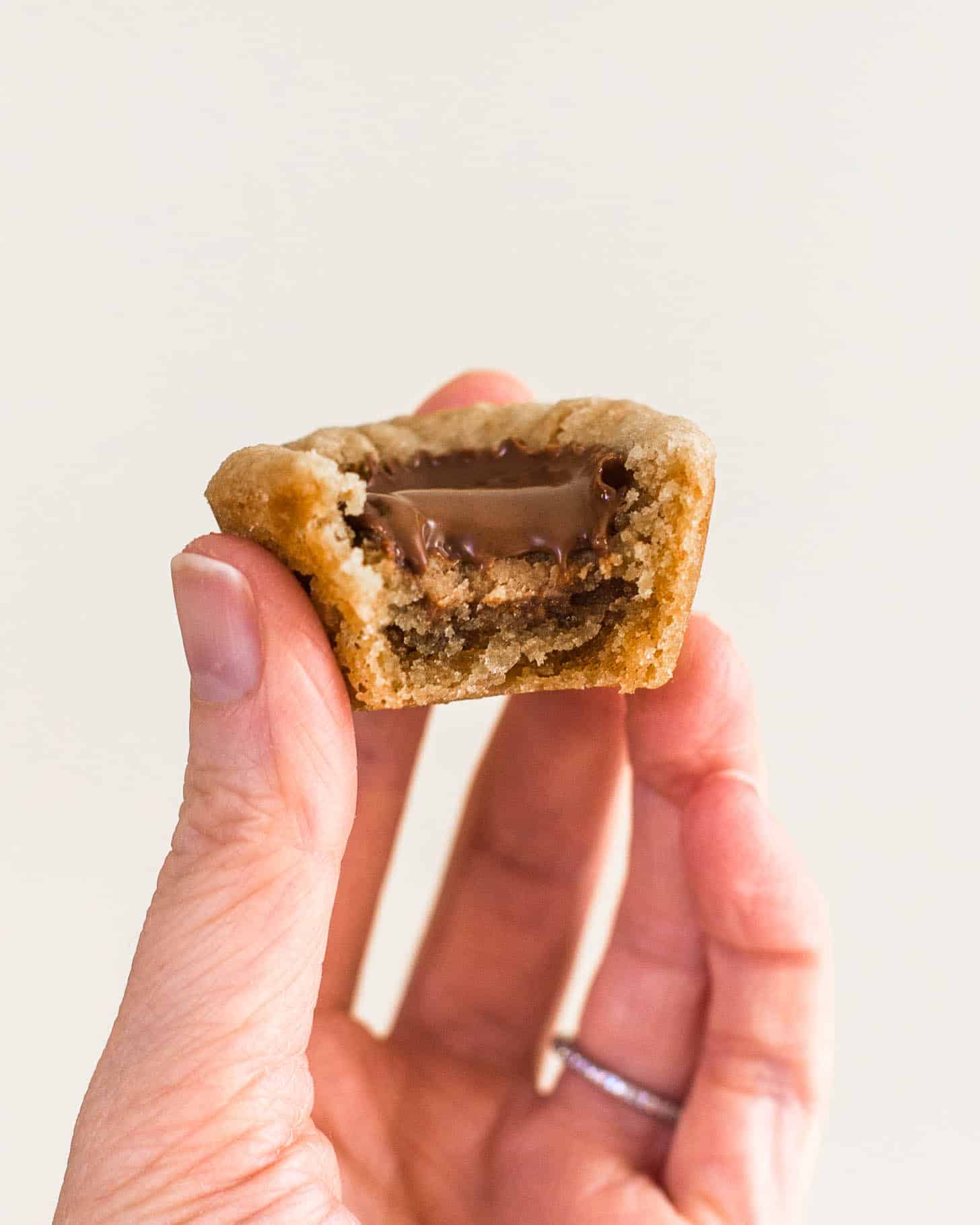 a hand holding a peanut butter cup cookie with a bite taken out 