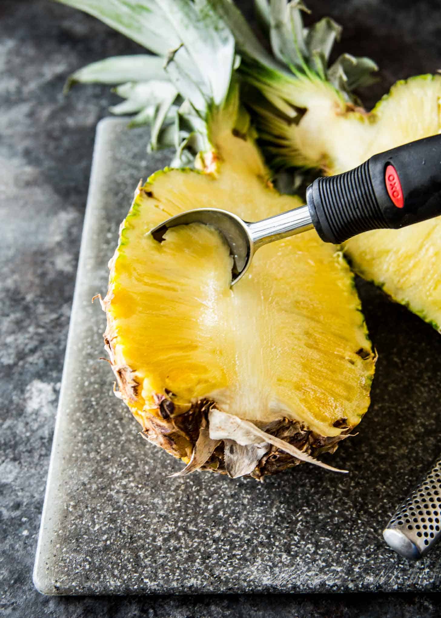 scooping out inside of half of pineapple