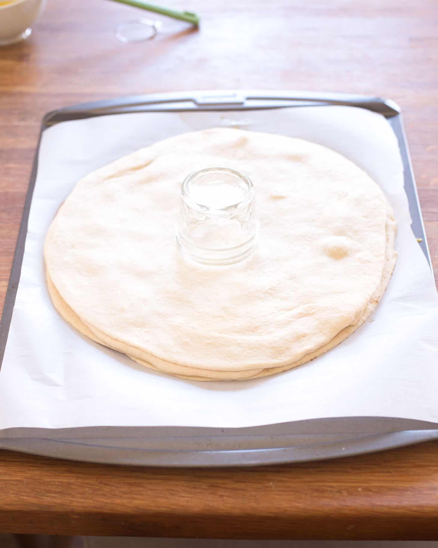 several layers of dough circles with a small glass jar in the middle