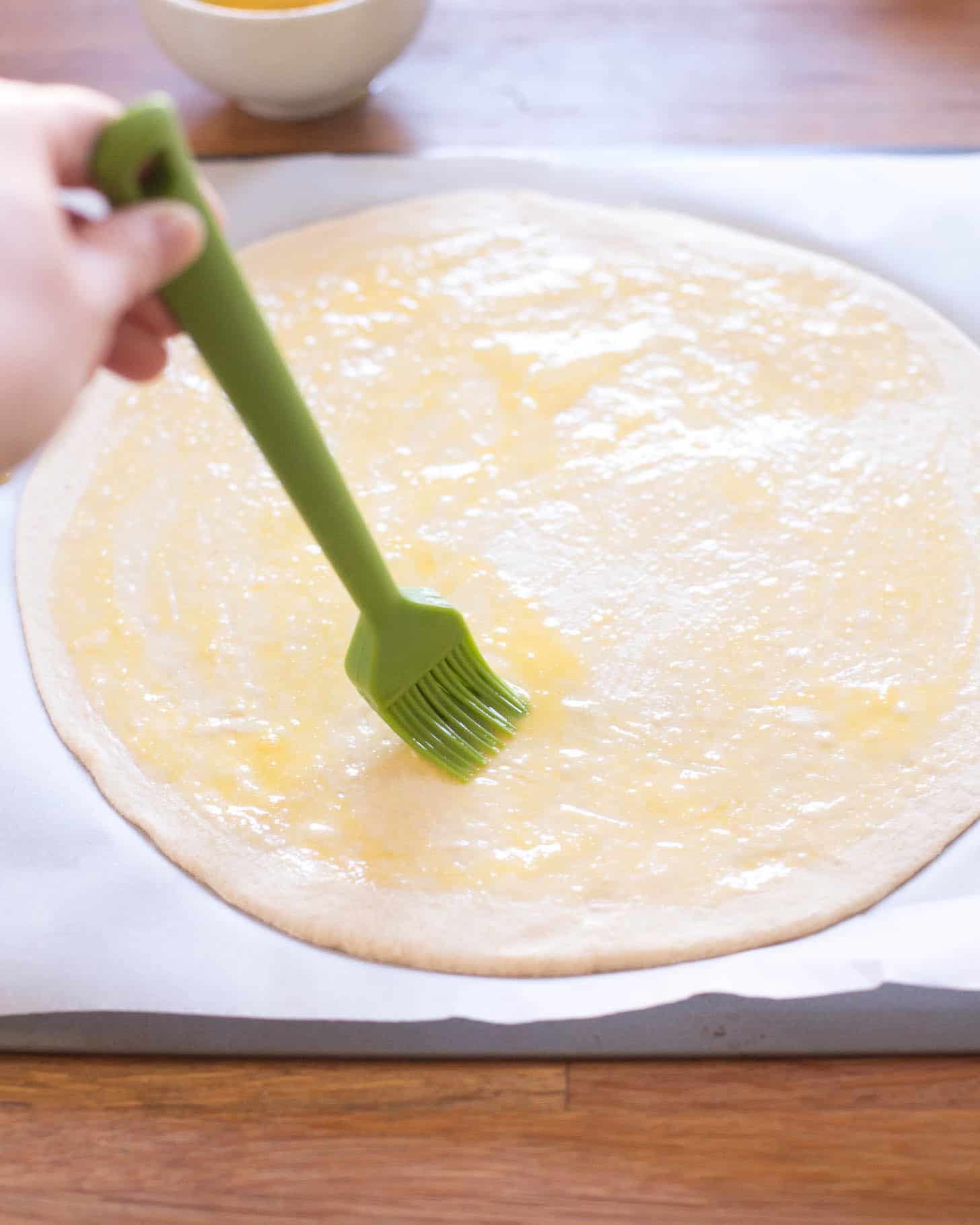 brushing dough circle with butter