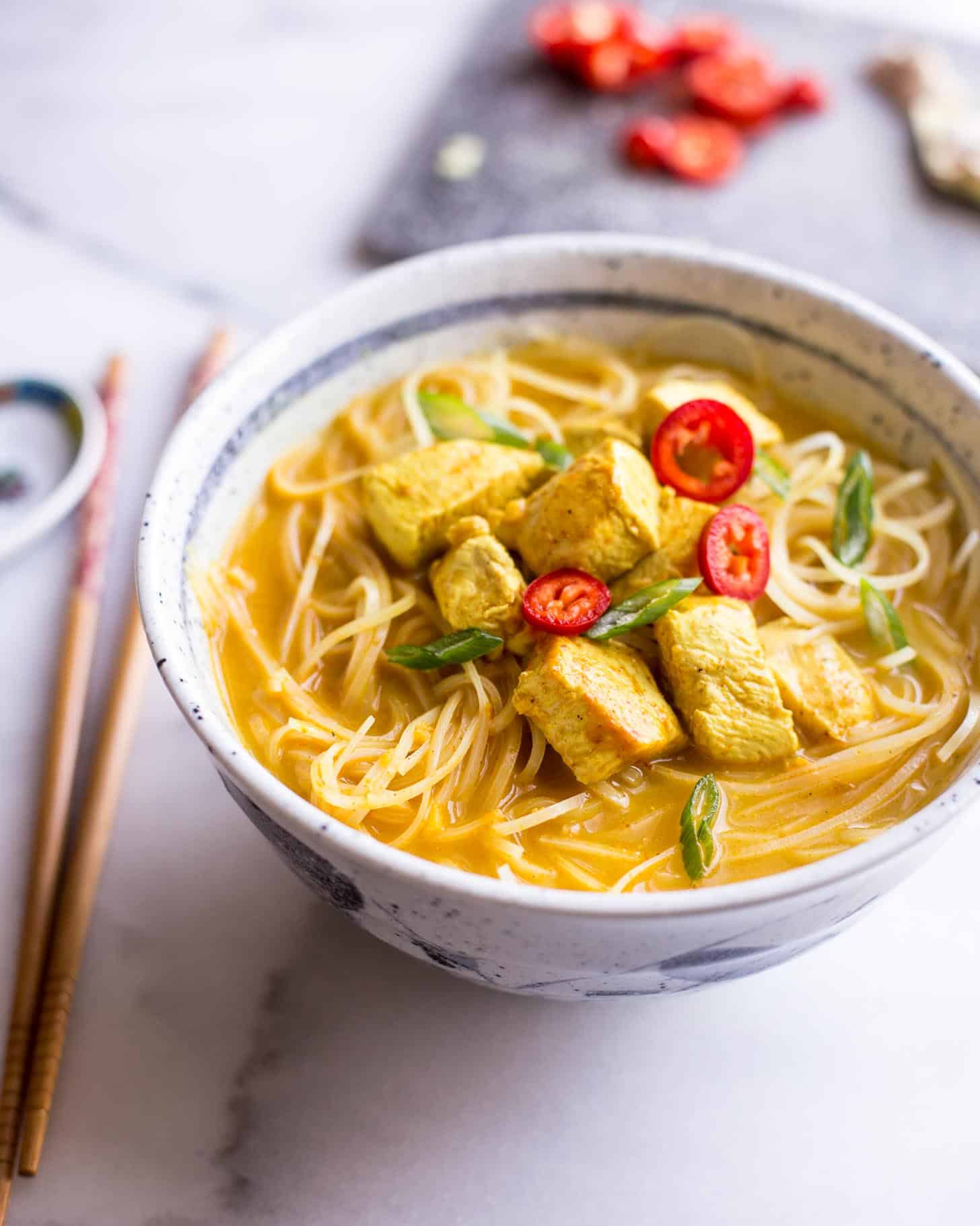 Thai Curry Noodle Soup with Chicken in a white and blue bowl