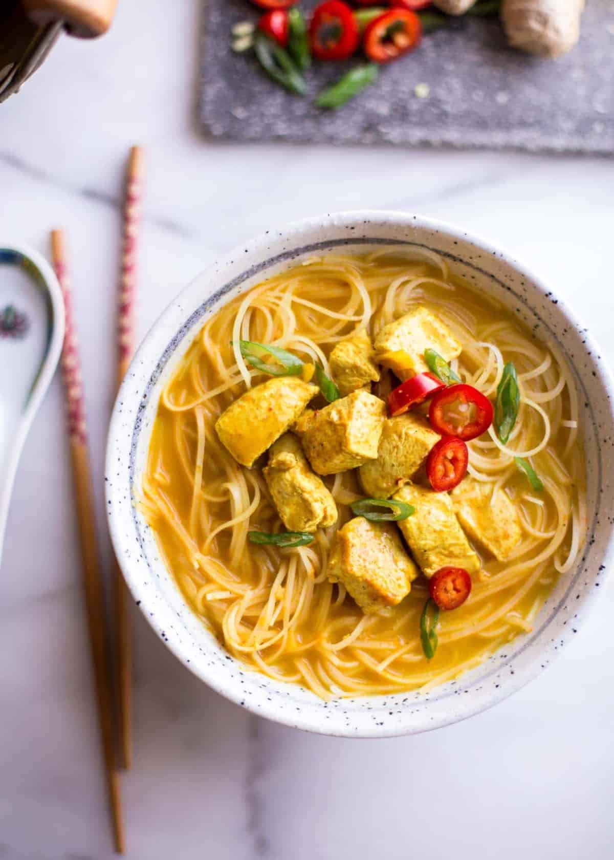 Thai Curry Noodle Soup with Chicken in a white bowl