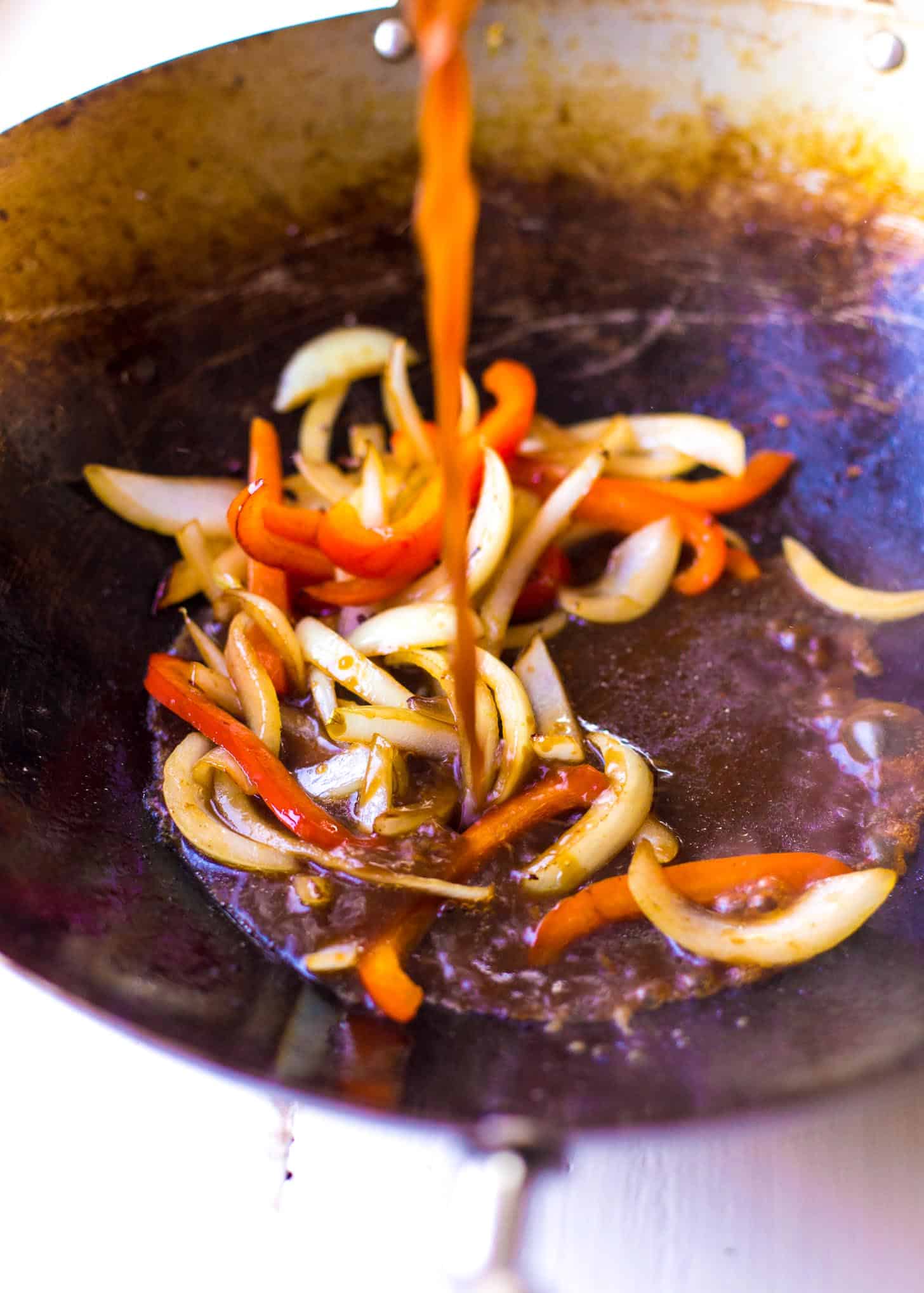 adding sauce to vegetables in a wok