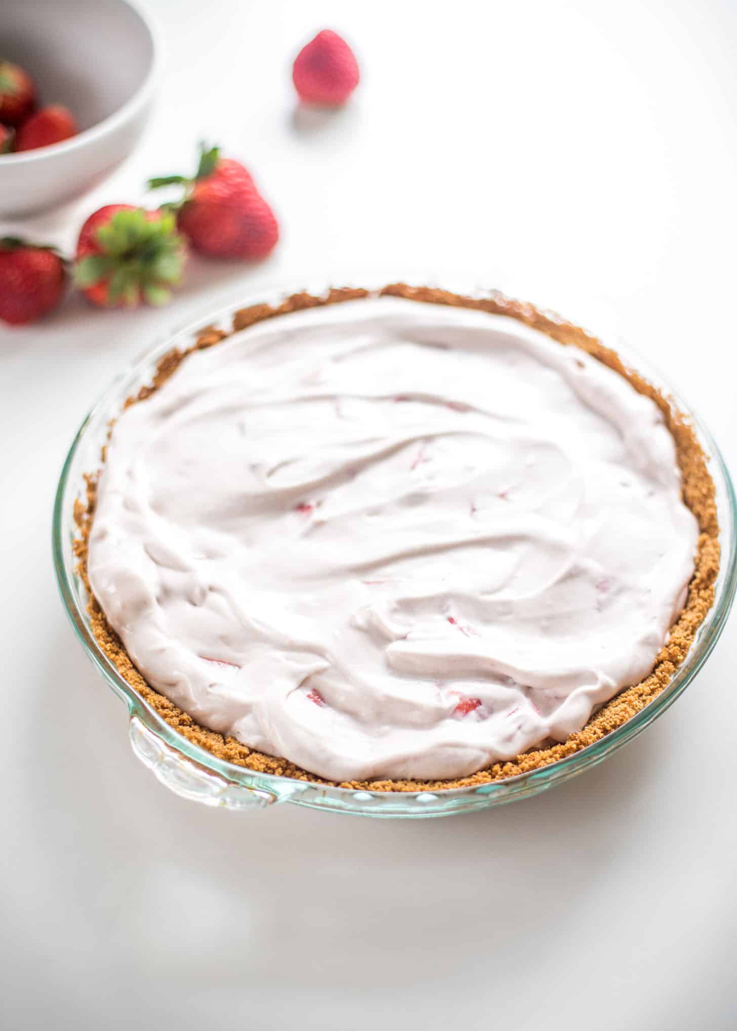 a strawberry cream pie in a clear pie dish