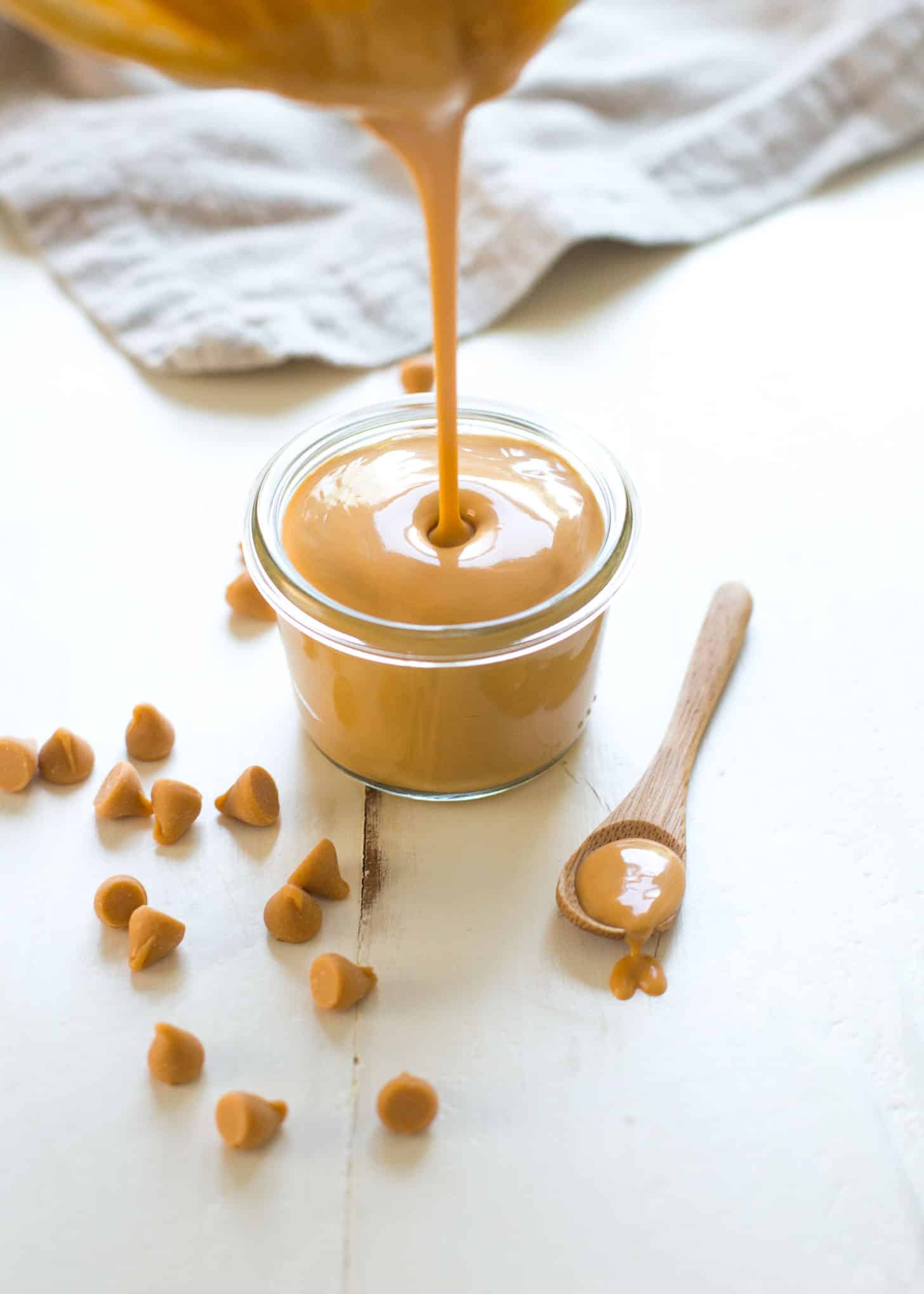 pouring butterscotch sauce into a clear jar