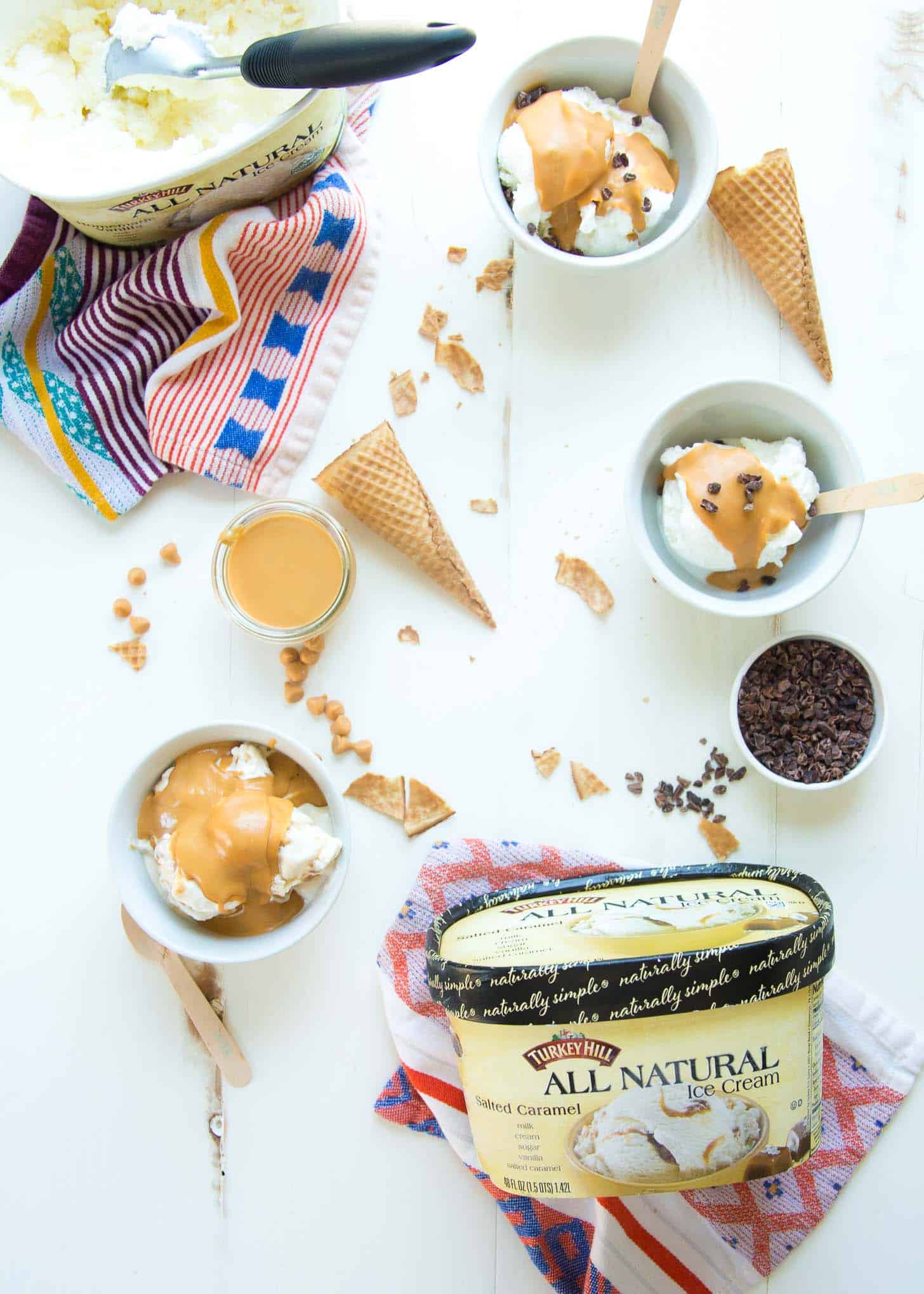 ice cream cones, ice cream, and chocolate chips on a white table