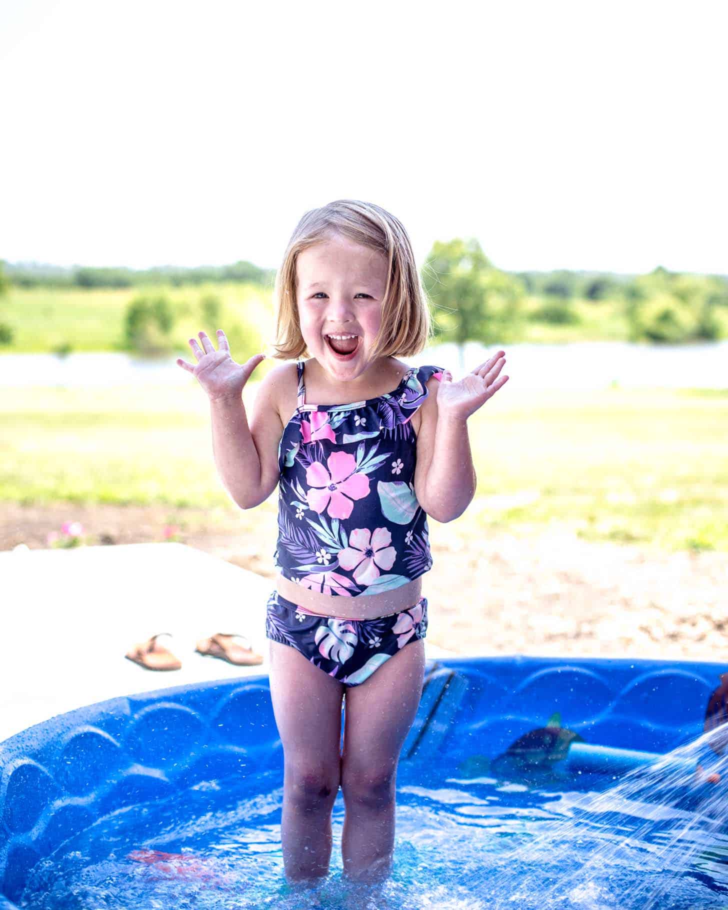 little girl with a happy face in a baby pool