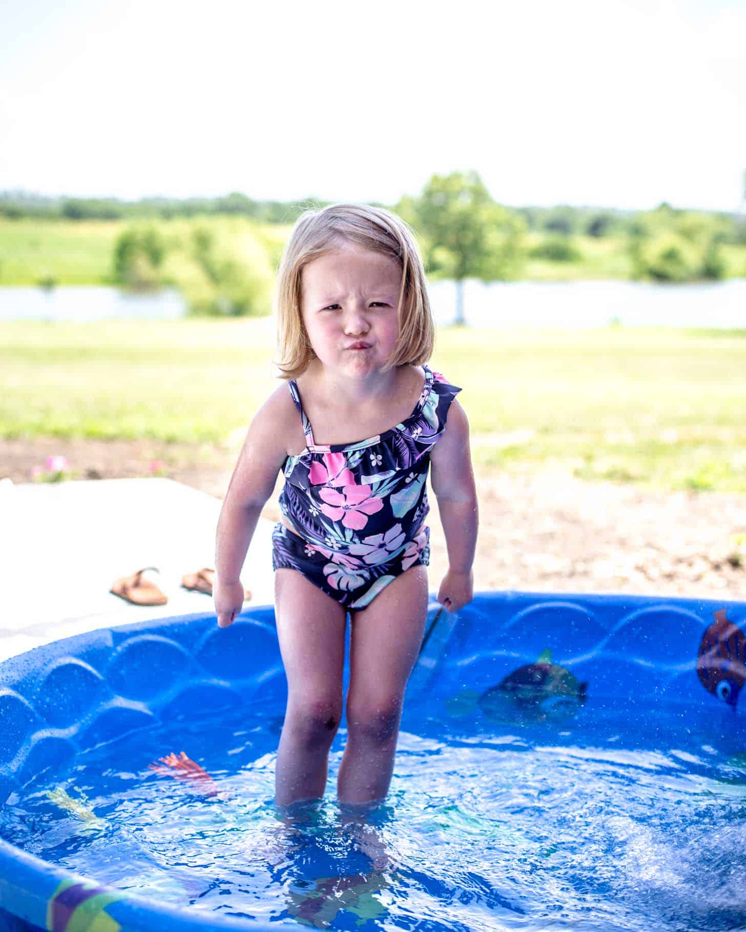 little girl with an angry face in a baby pool