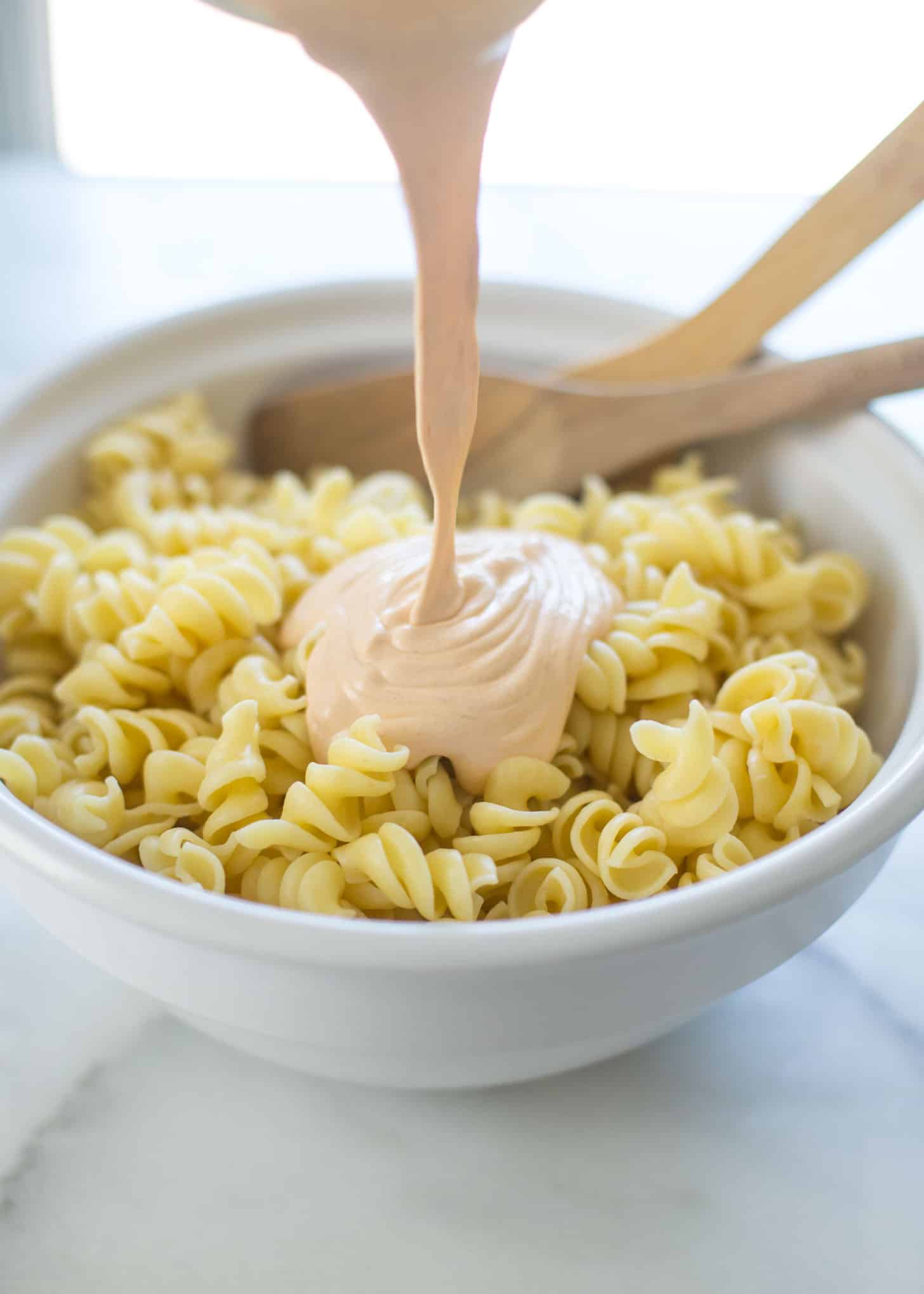 pouring chipotle dressing over pasta