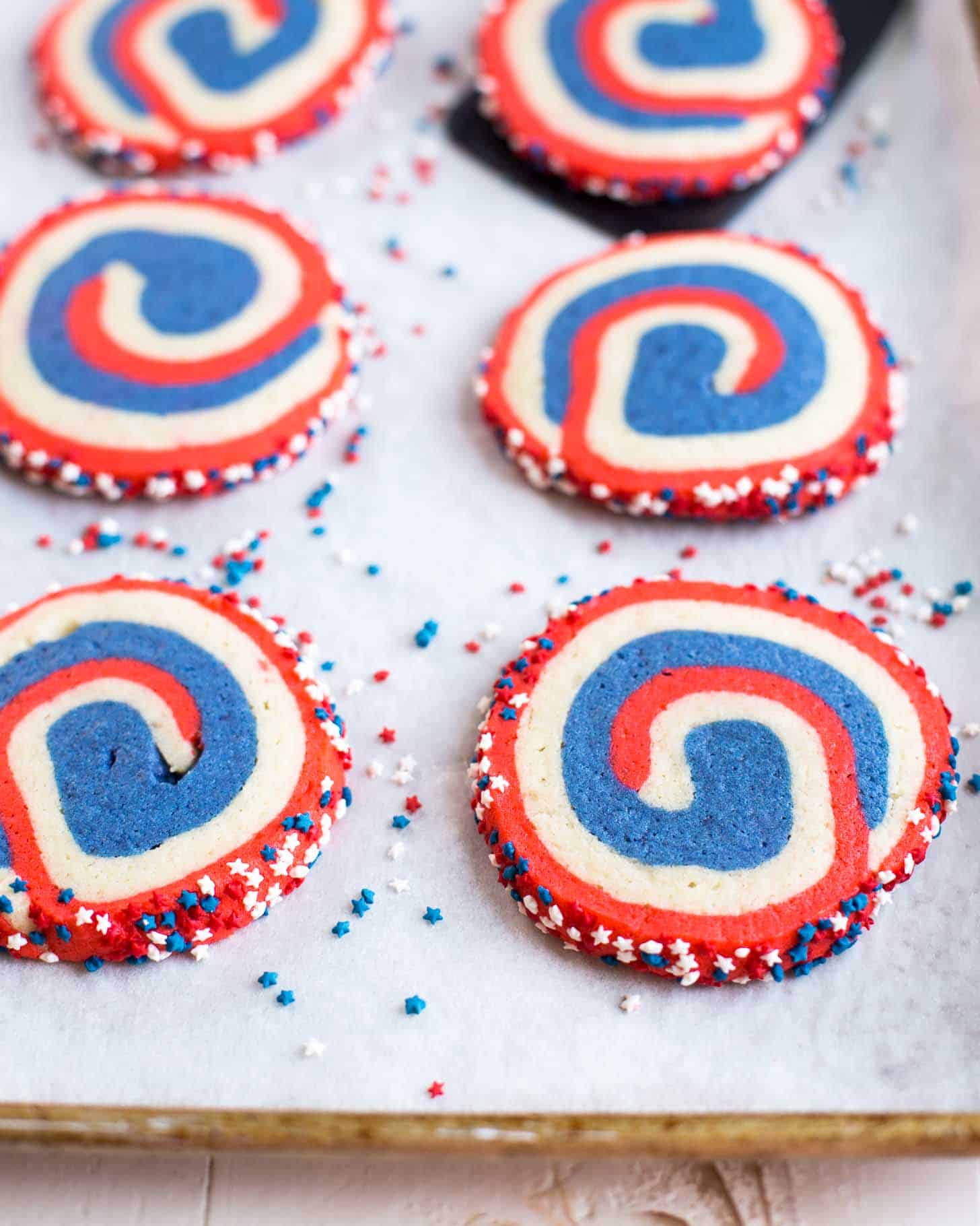 sliced pinwheel cookies on a parchment lined sheet pan