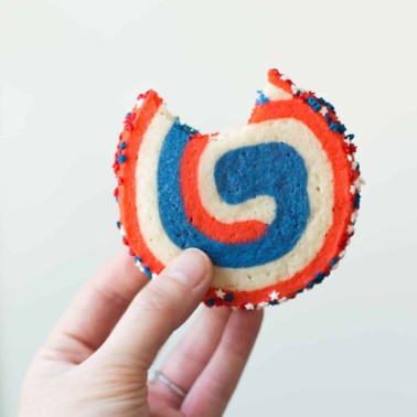 a hand holding a red, white and blue pinwheel cookie