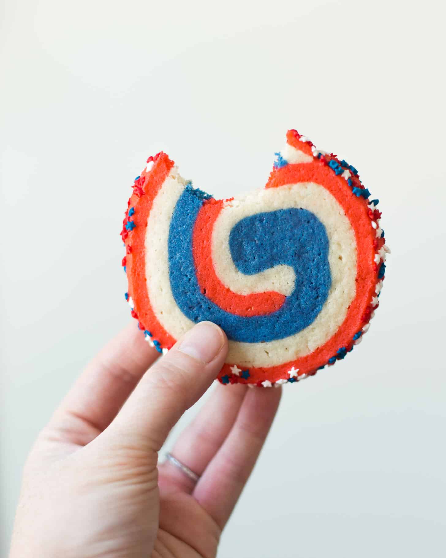 a hand holding a red, white and blue pinwheel cookie