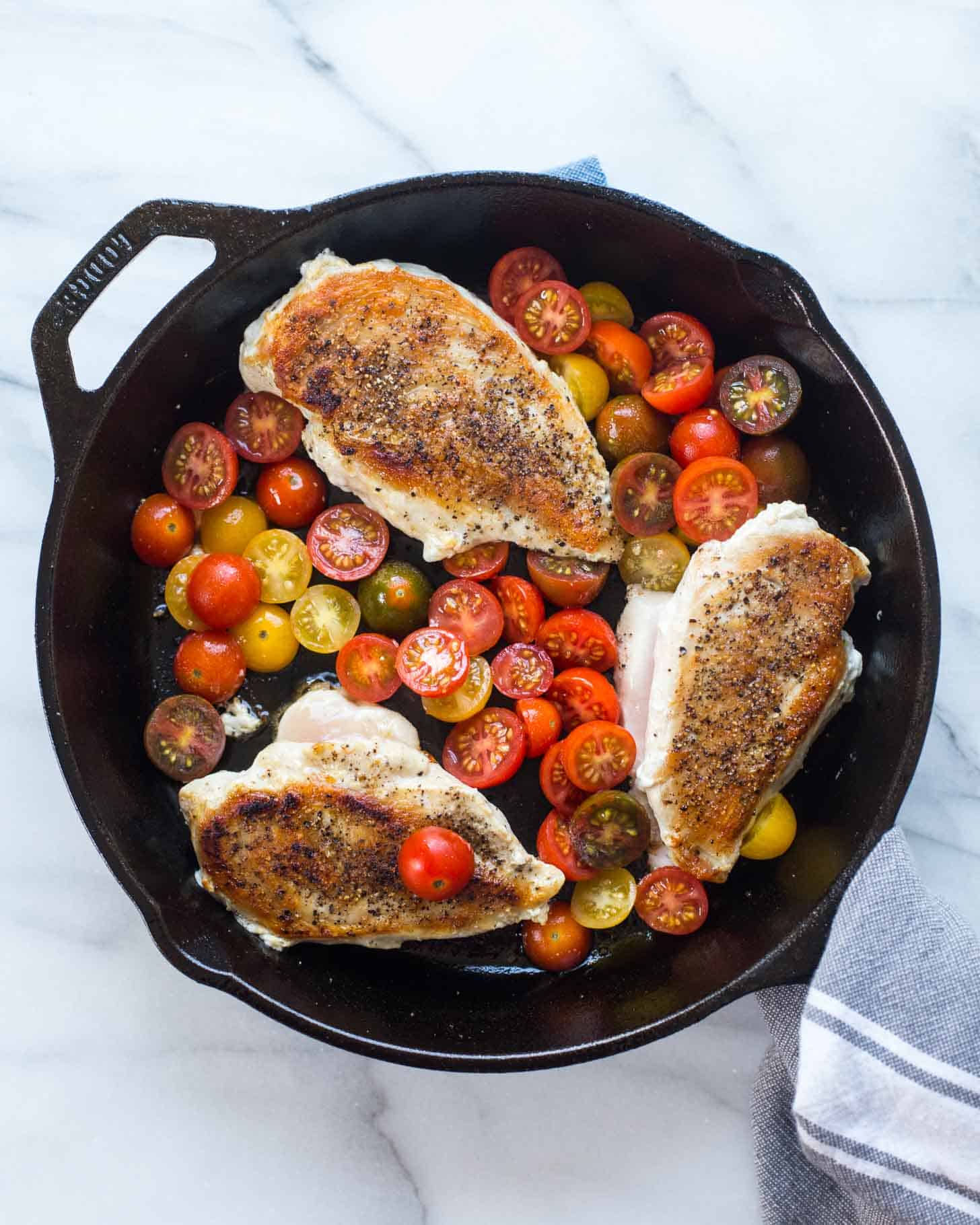 chicken breasts and cherry tomatoes in a cast iron skillet