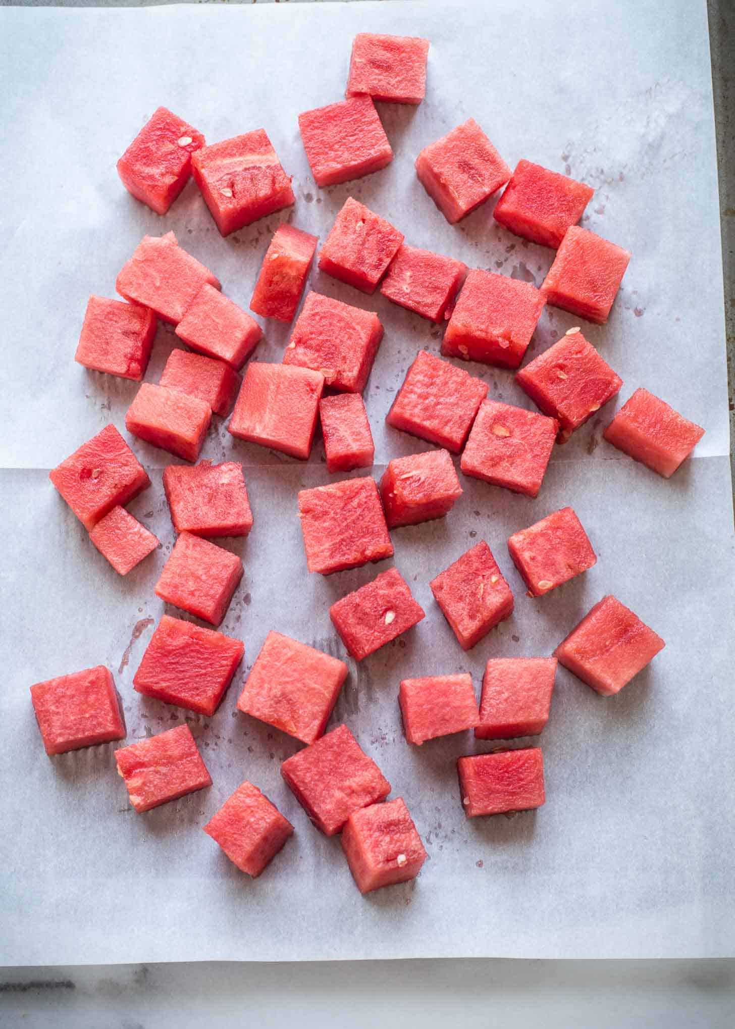 overhead image of cubes of watermelon on a parchment lined tray