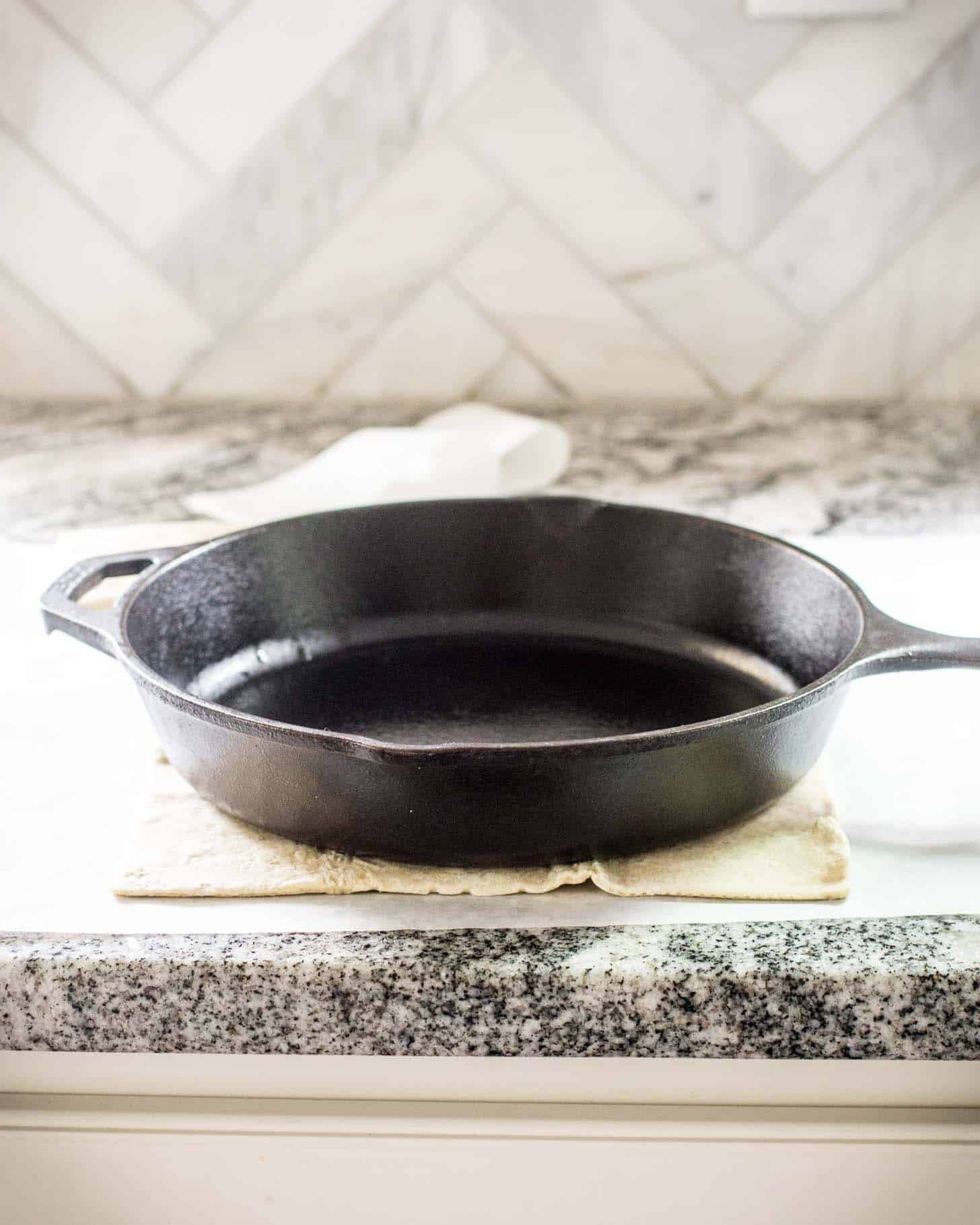 a cast iron skillet resting on dough on a countertop