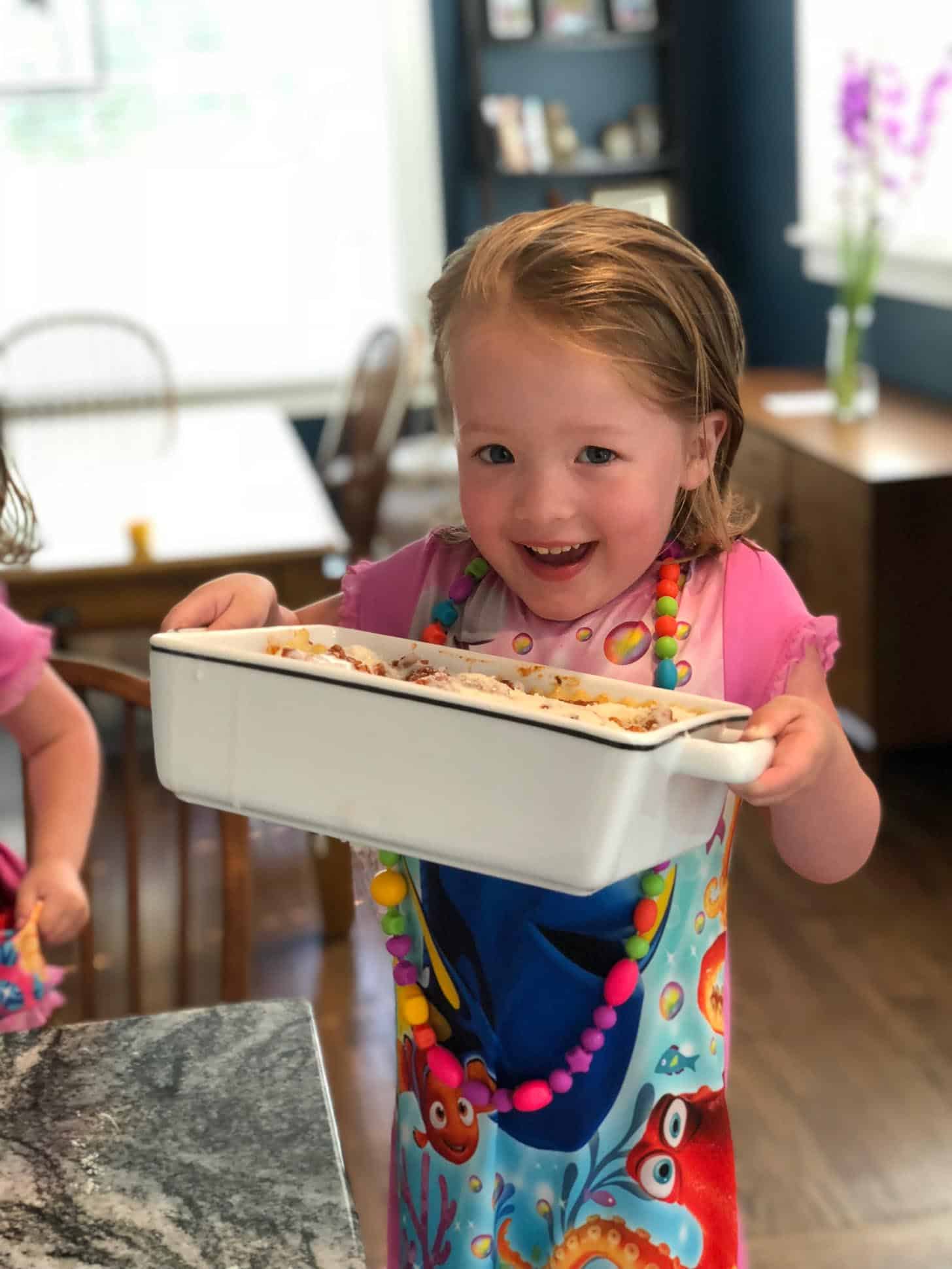 little girl holding lasagna