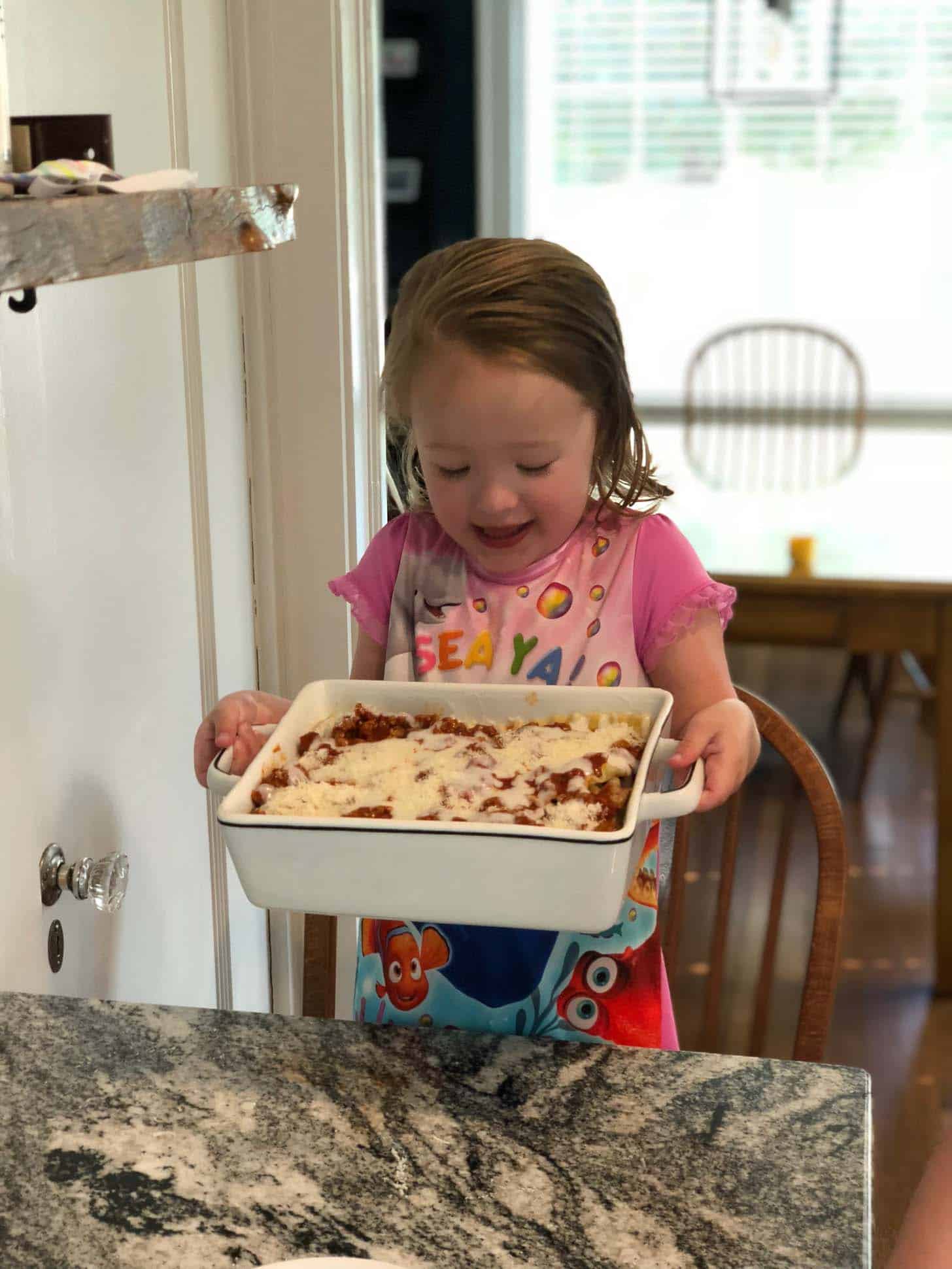 little girl holding lasagna