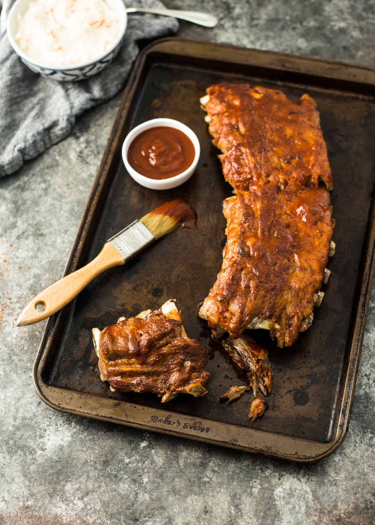 Instant Pot BBQ Ribs on a sheet pan with bbq sauce and a brush