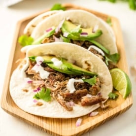 carnitas tacos on a wooden tray