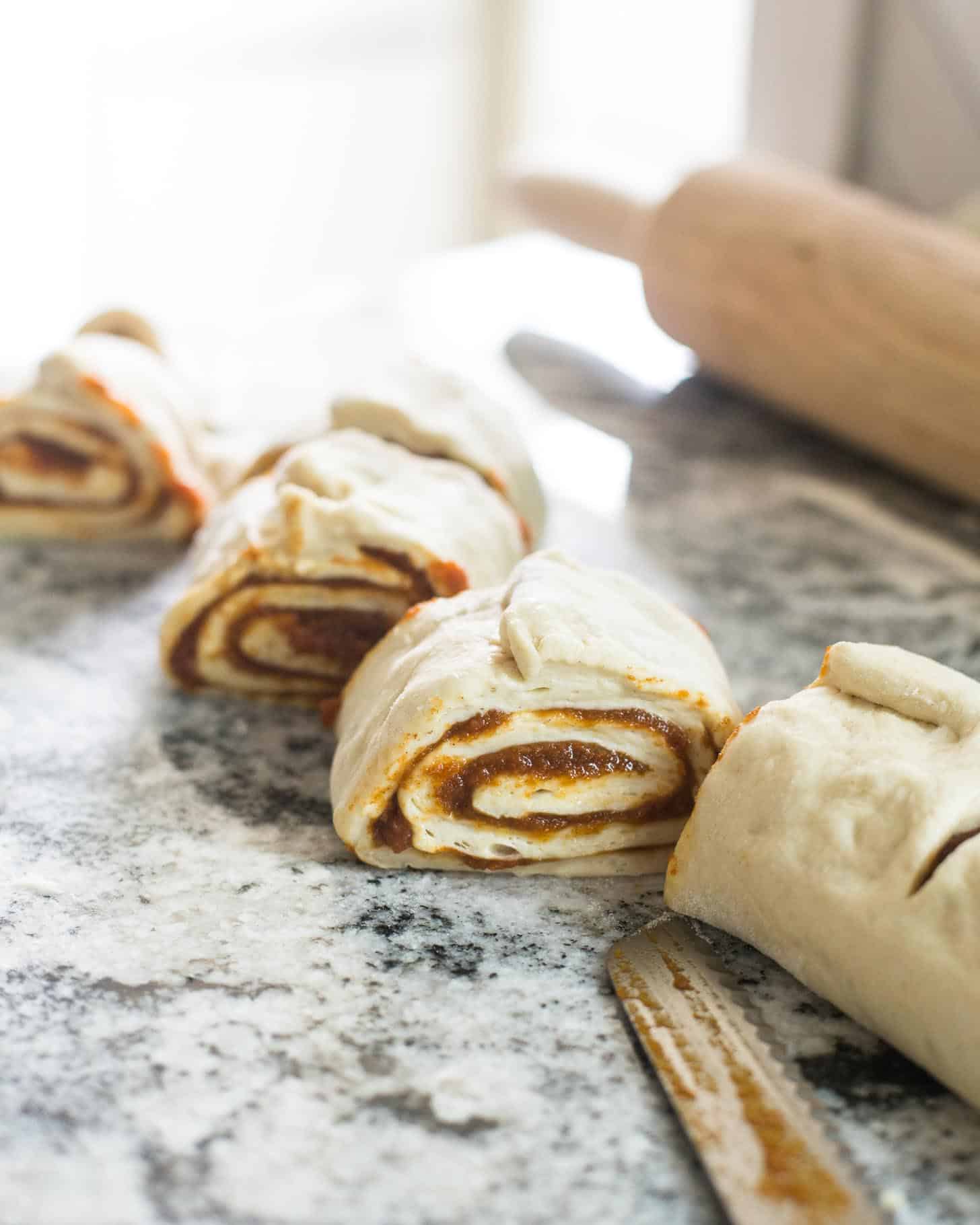 cutting dough into cinnamon rolls