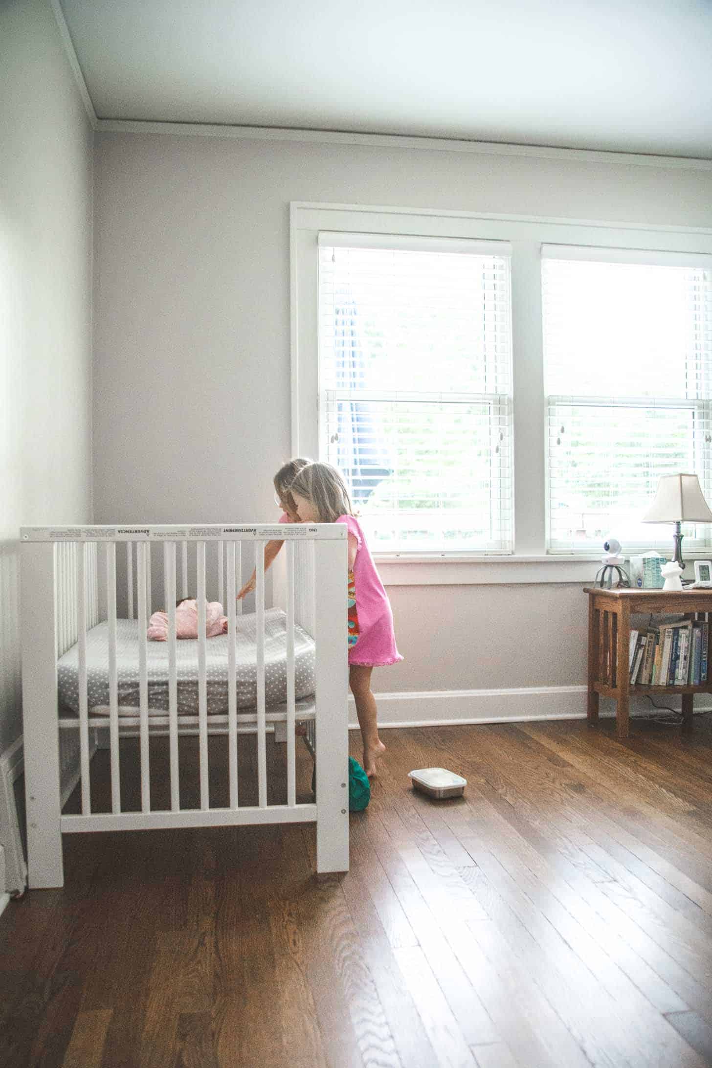 two little girls looking at a baby in a crib