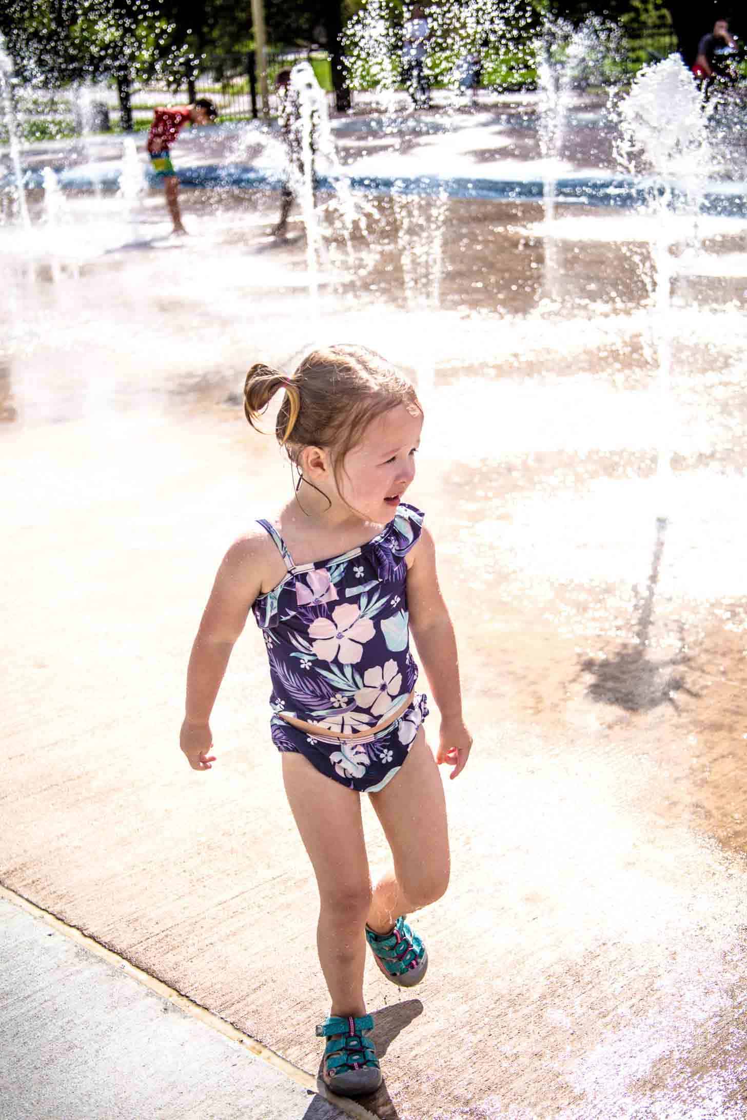 a little girl in a bathing suit playing in the water