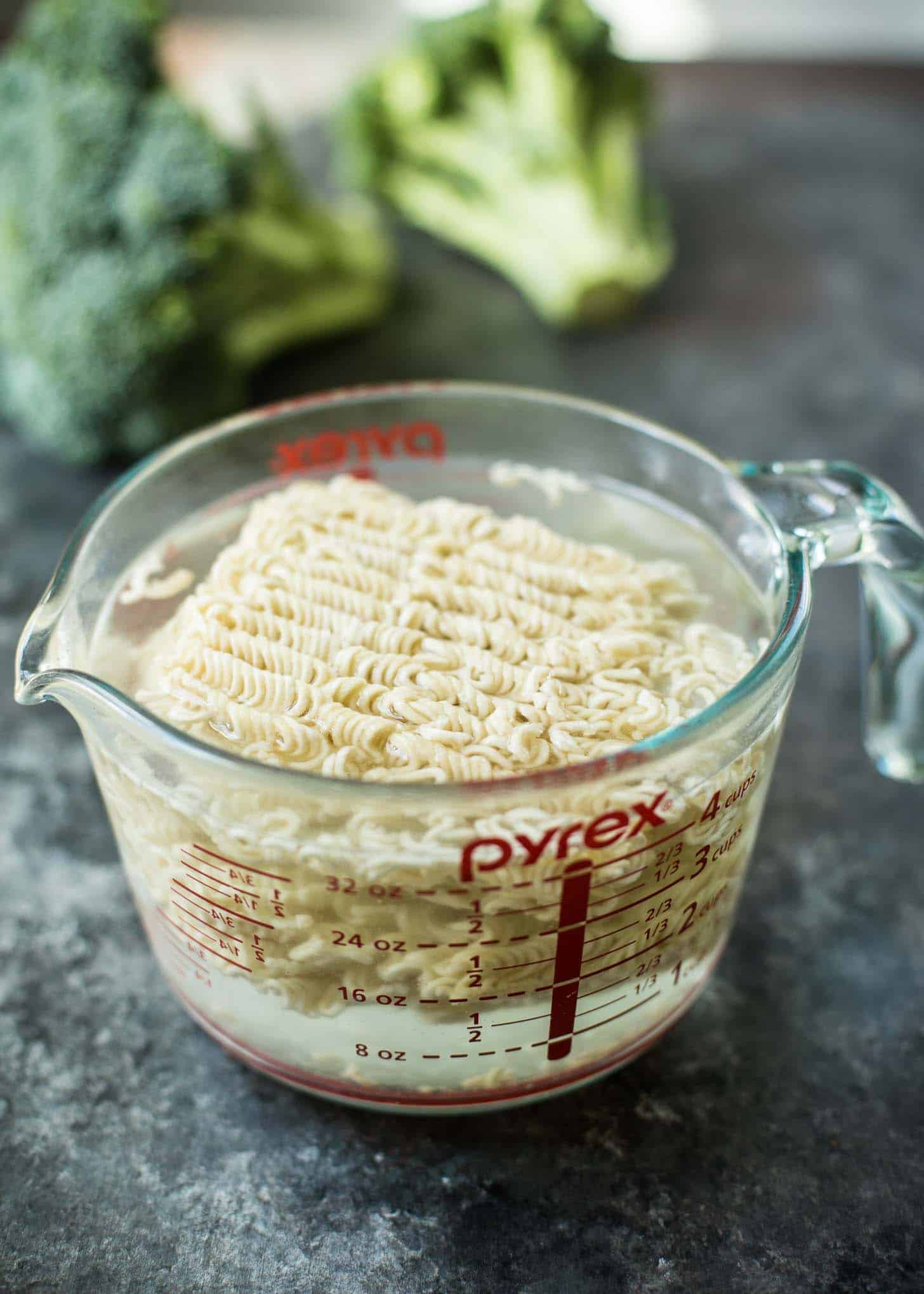 soaking ramen noodles in hot water in a large glass measuring cup