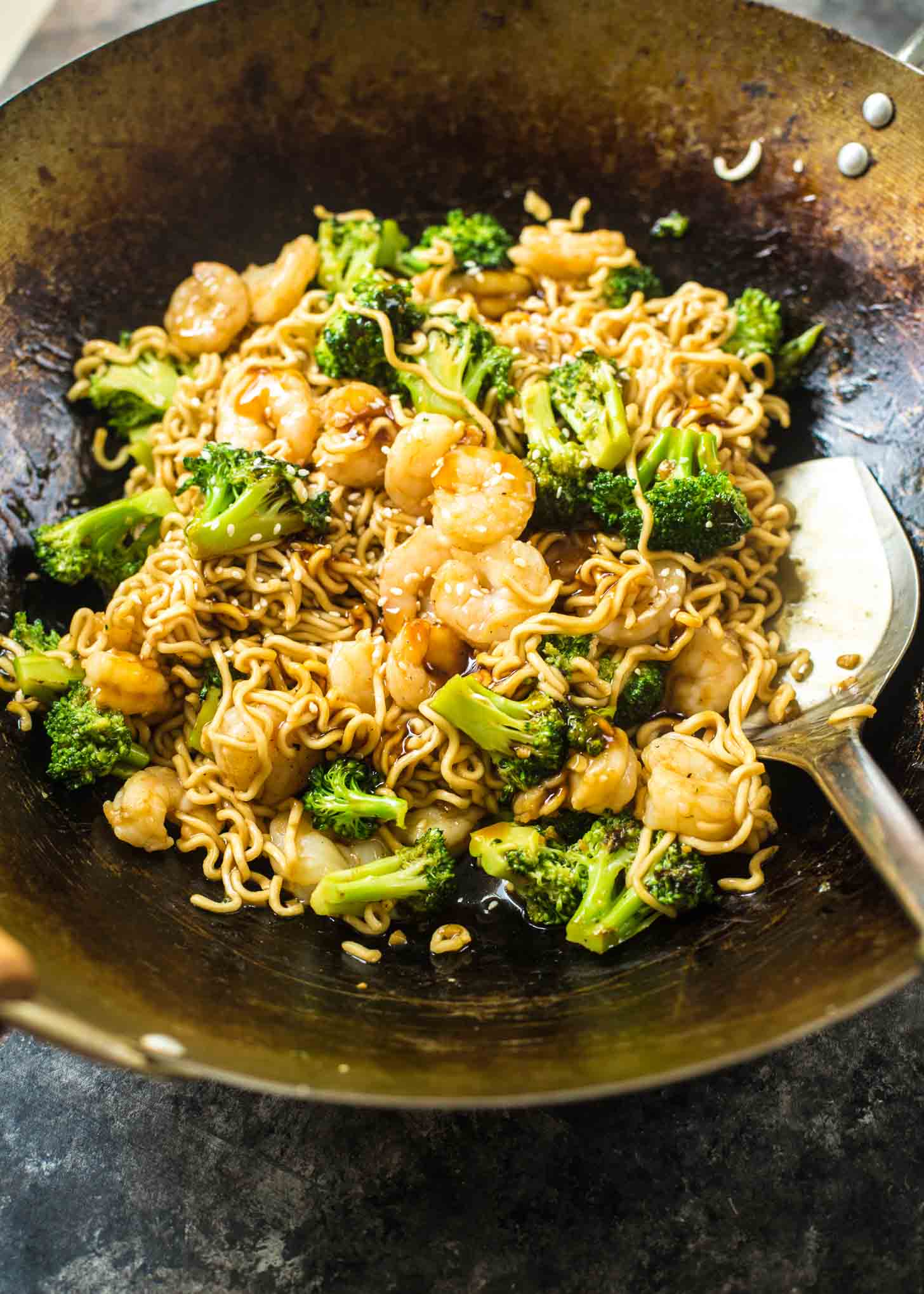 overhead image of a spatula stirring teriyaki shrimp and noodles in a wok