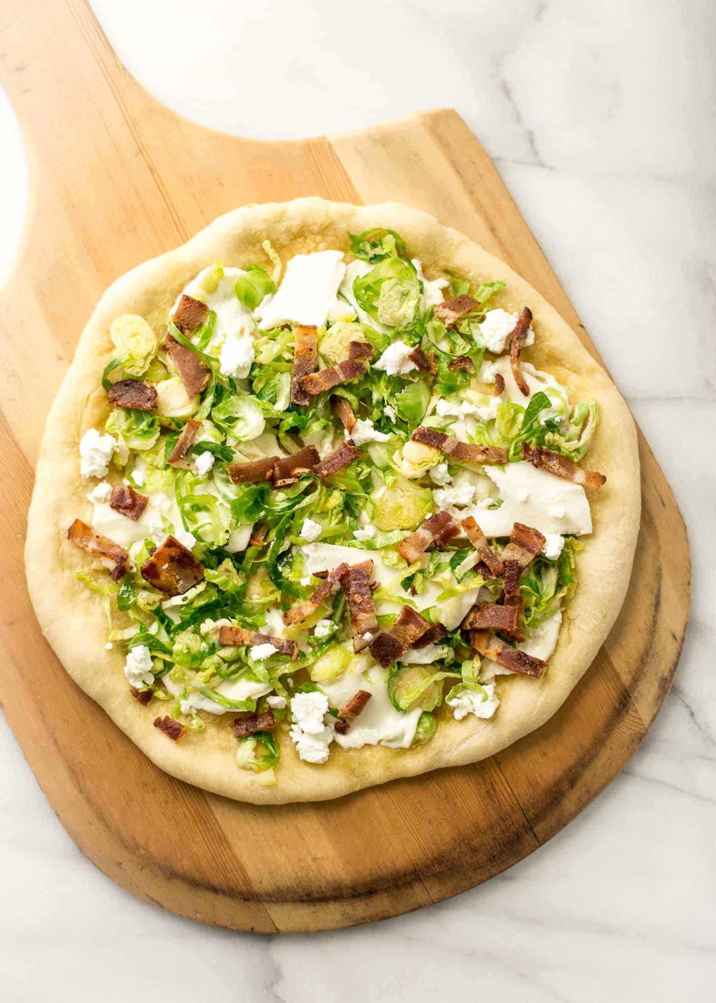 overhead image of uncooked Pizza on a wooden pizza peel