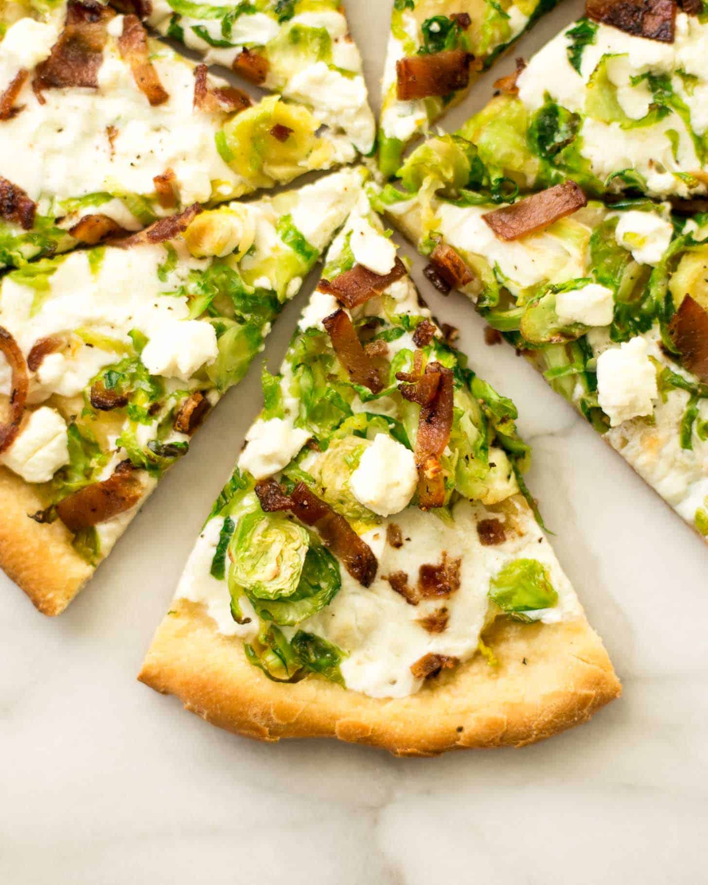 overhead image of Brussels Sprouts, Bacon, and Goat Cheese Pizza cut into slices