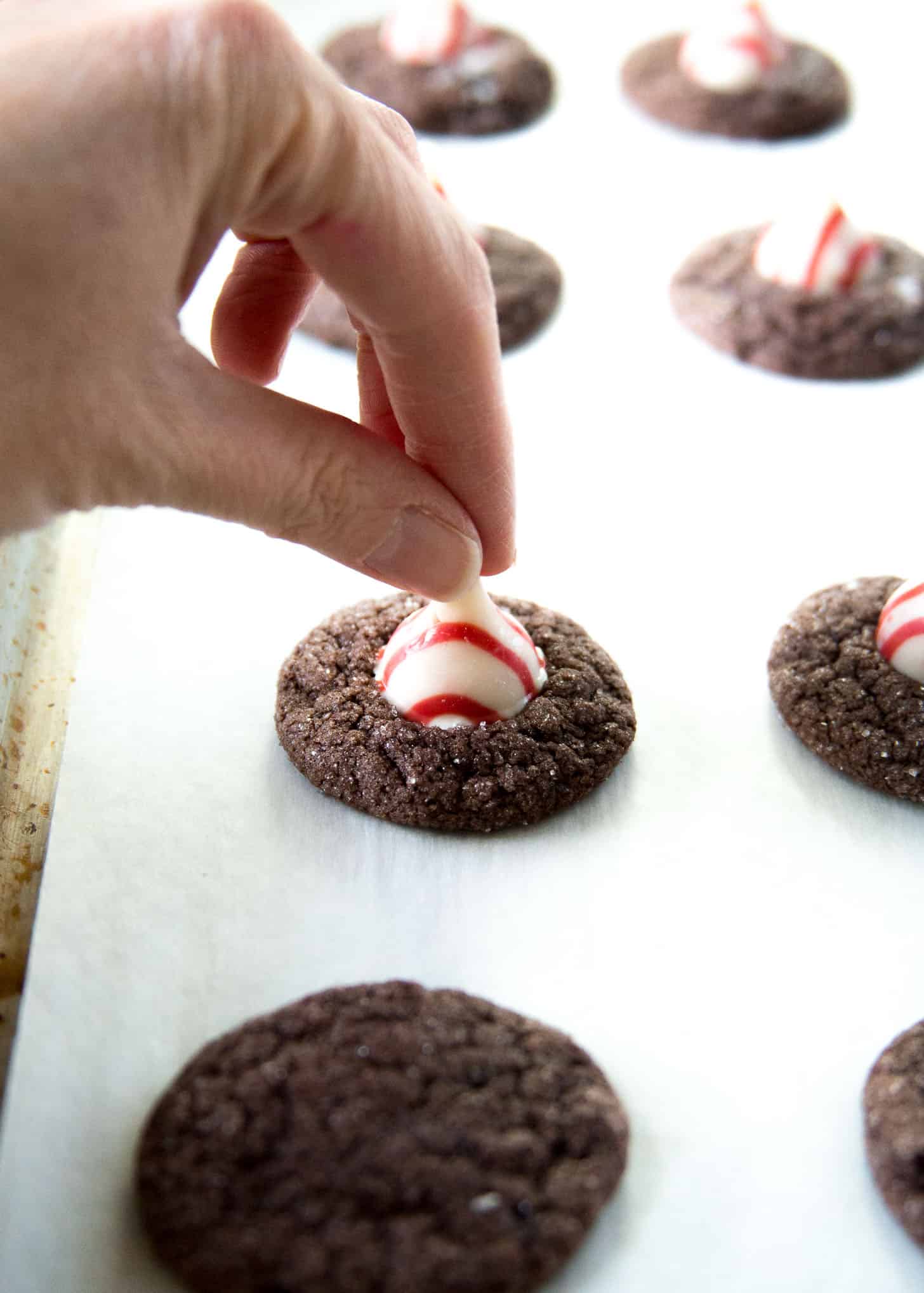 adding peppermint kisses to the top of chocolate cookies