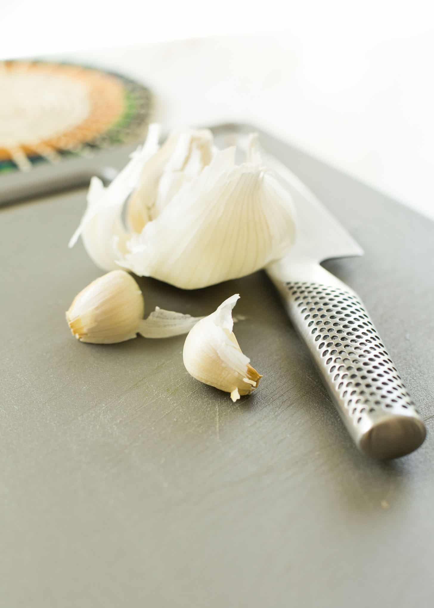 cloves of garlic on a grey cutting board