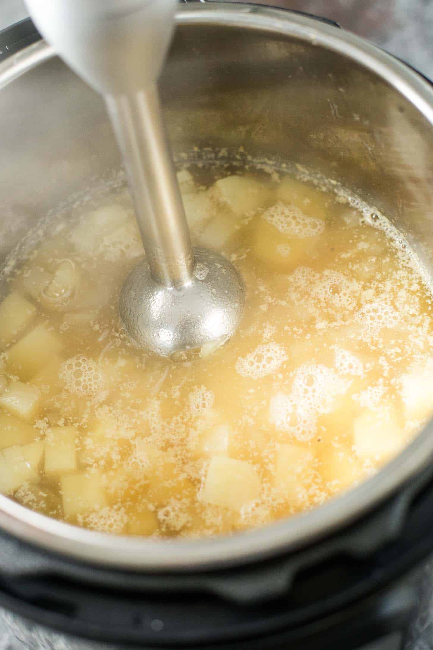 using an immersion blender to puree potatoes for soup