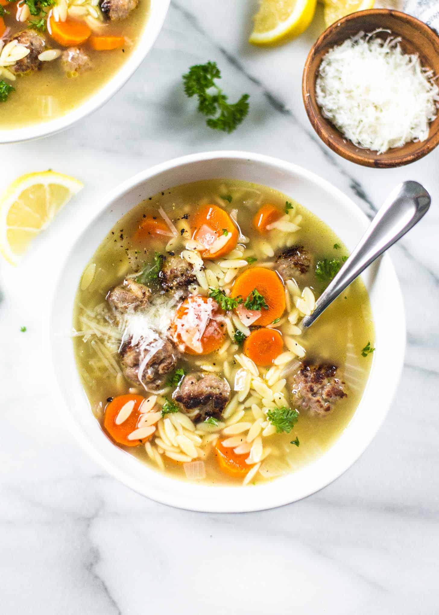 overhead image of Mini Meatball and Orzo Soup in a white bowl with a spoon