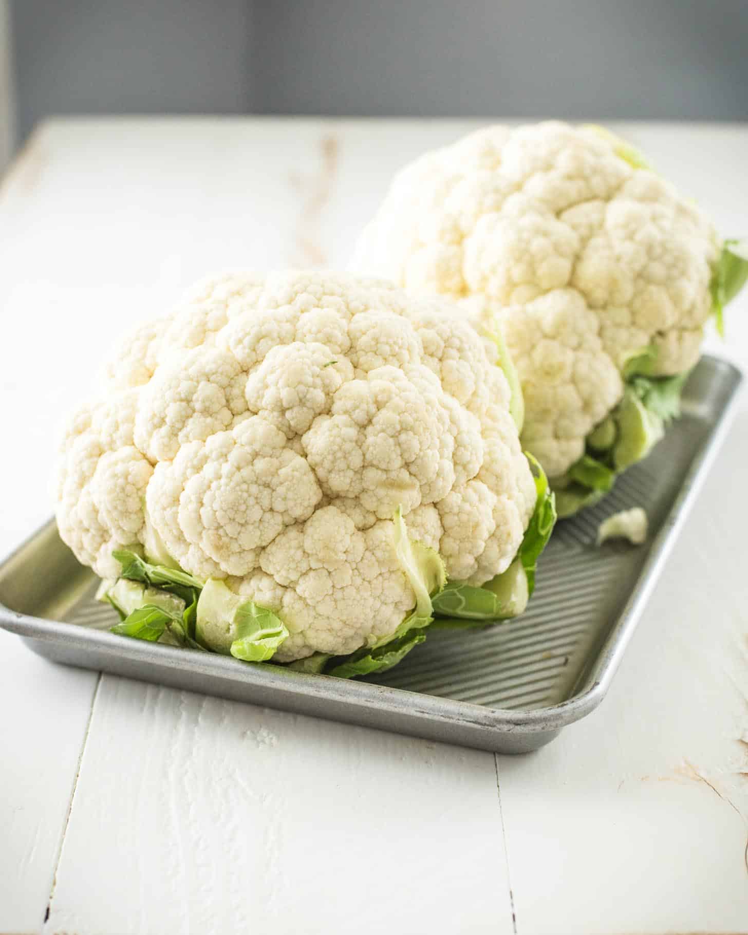 raw heads of cauliflower on a sheet pan